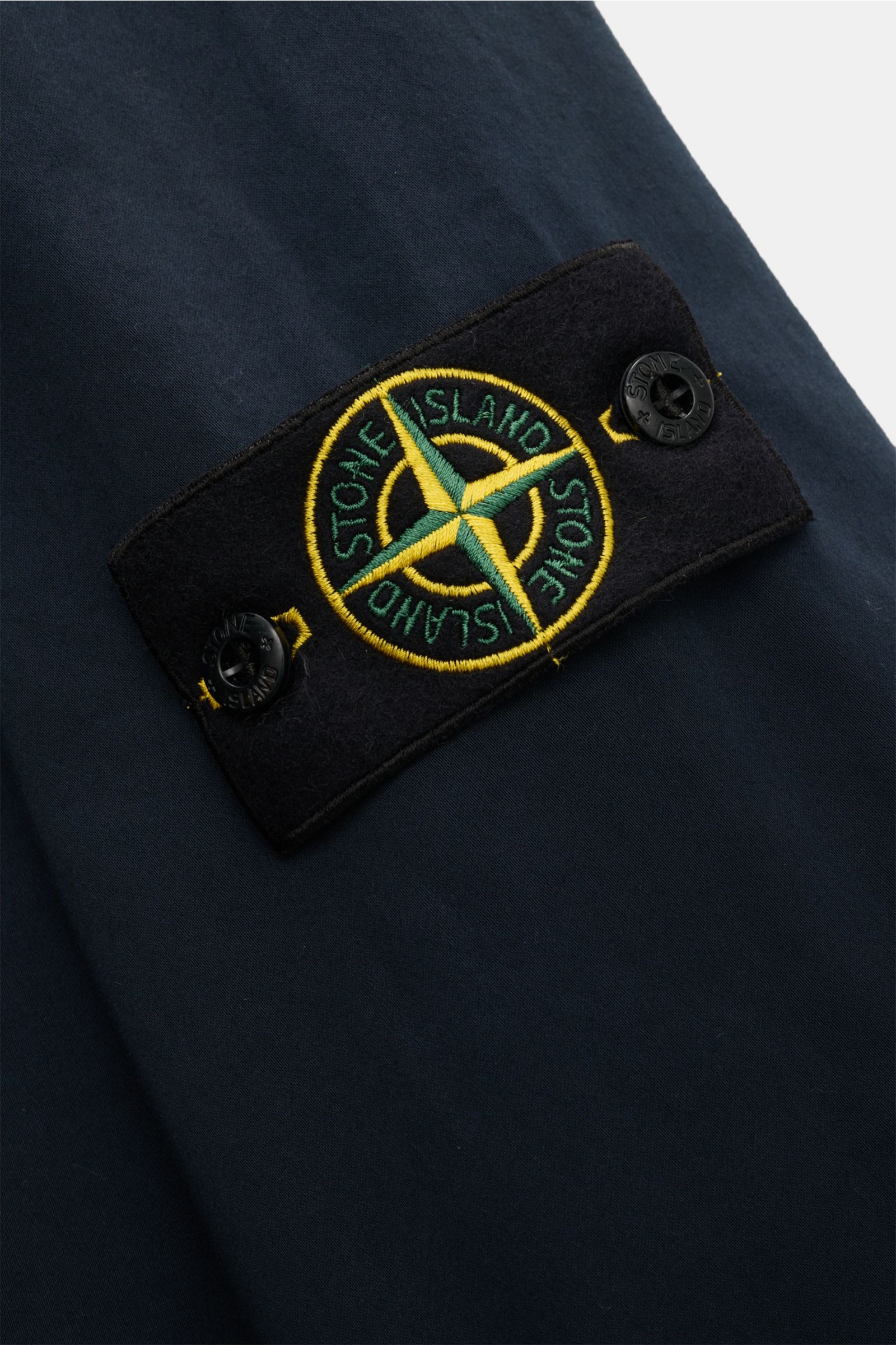 Close-up view of the Stone Island Overshirt navy showing the black patch with yellow and green embroidered compass badge on navy cotton popeline fabric.

Sportives Overshirt: Dieser Hybrid in typischer STONE ISLAND-Manier ist aus feinem Baumwoll-Popeli
