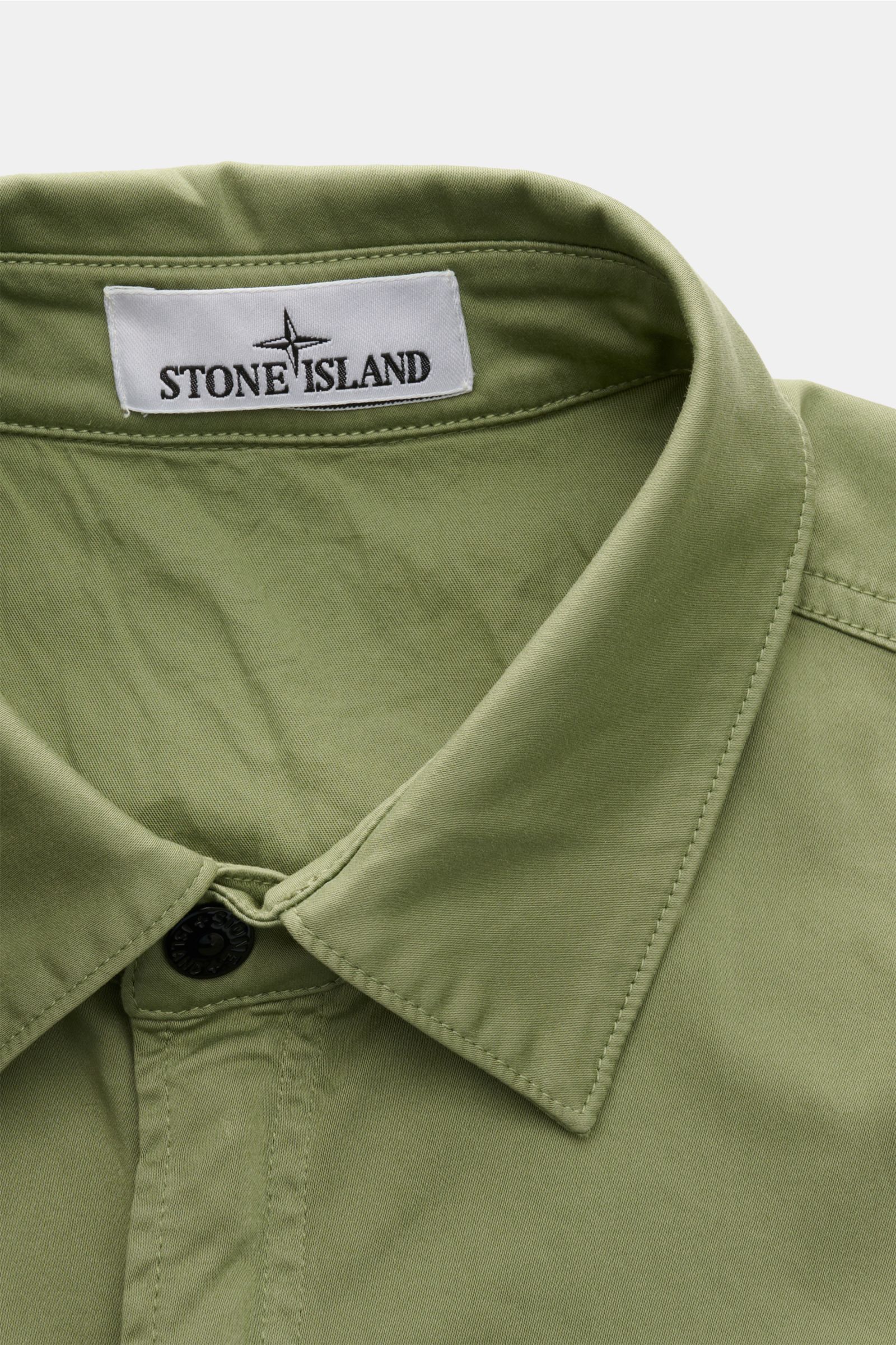 Nahaufnahme des graugrünen Stone Island Overshirts aus Baumwoll-Popeline mit Umlegekragen, Markenlabel innen, fotografiert von oben.