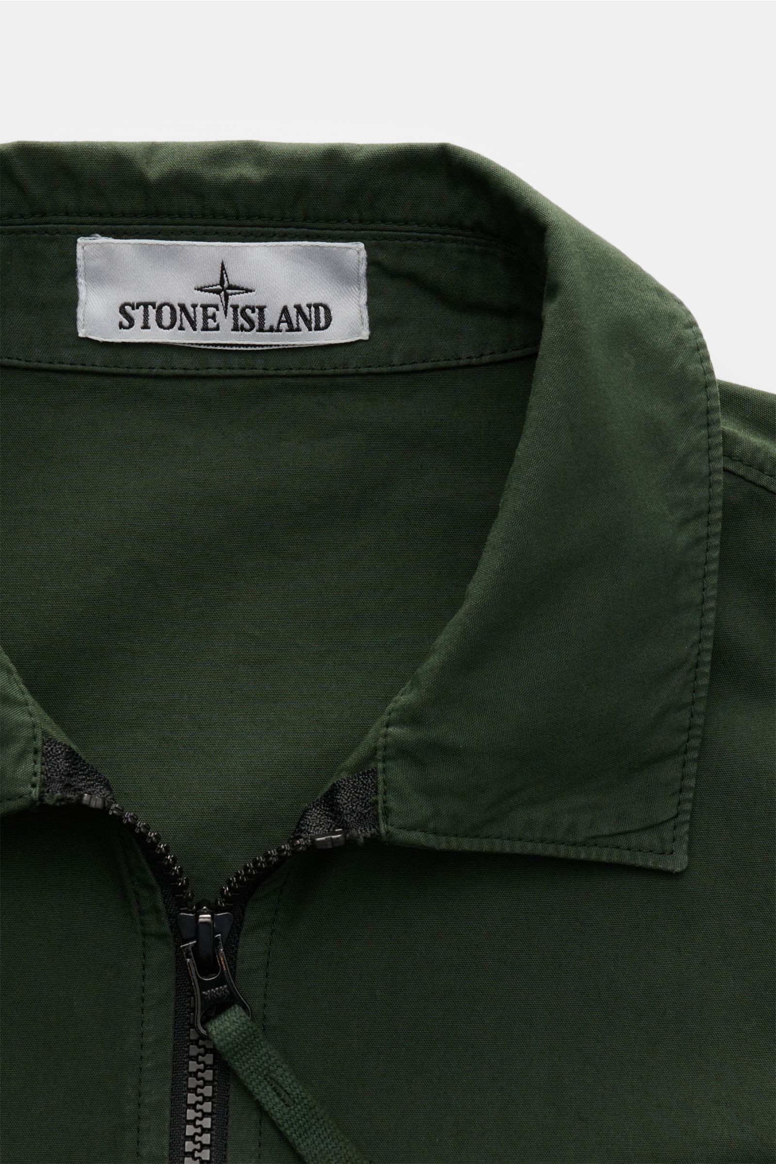 Stone Island Overshirt 'Canvas Weave' dunkelgrün, Nahaufnahme von oben, Canvas aus reiner Baumwolle, Slim Fit, robuster Zwei-Wege-Reißverschluss, Umlegekragen, Brusttasche mit Zipper und Knopf, Kompass-Badge am Ärmel, Ärmel mit Druckknopf, ungefüttert.