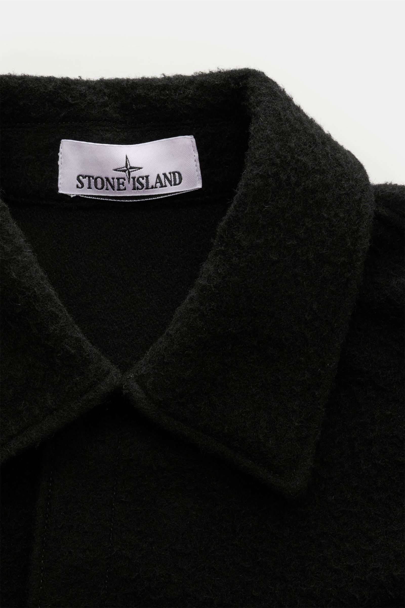 Nahaufnahme der Stone Island Jacke 'Panno Ratinato' schwarz von oben, Mix aus Wolle und Microfaser, strukturierte Haptik, Slim Fit, Druckknopfleiste, Umlegekragen, typisches Kompass-Badge am Ärmel, Ärmelabschlüsse mit Druckknopf, regulierbare Saumweite.