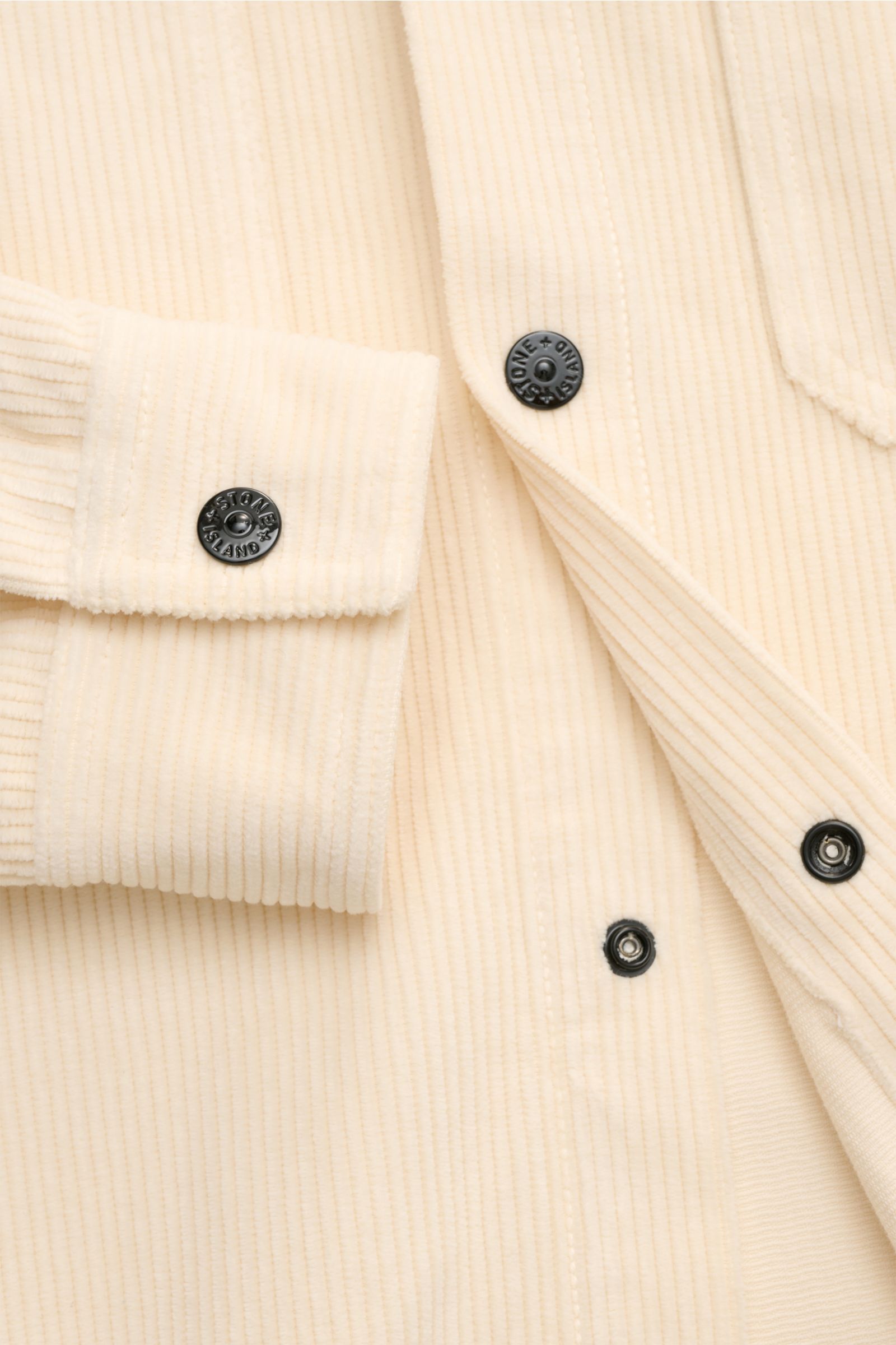 Nahaufnahme des Stone Island Cord Overshirt 'Organic Cotton Corduroy' creme, zeigt Druckknopfleiste und Manschette aus weichem Bio-Baumwoll-Cord.