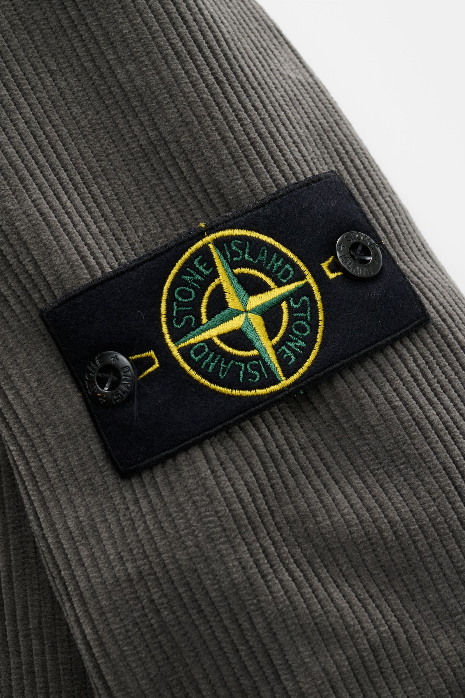 Stone Island Cord Overshirt 'Organic Cotton Corduroy' dunkelgrau Detailaufnahme des typischen Kompass-Badges am Ärmel aus Bio-Baumwoll-Cord.