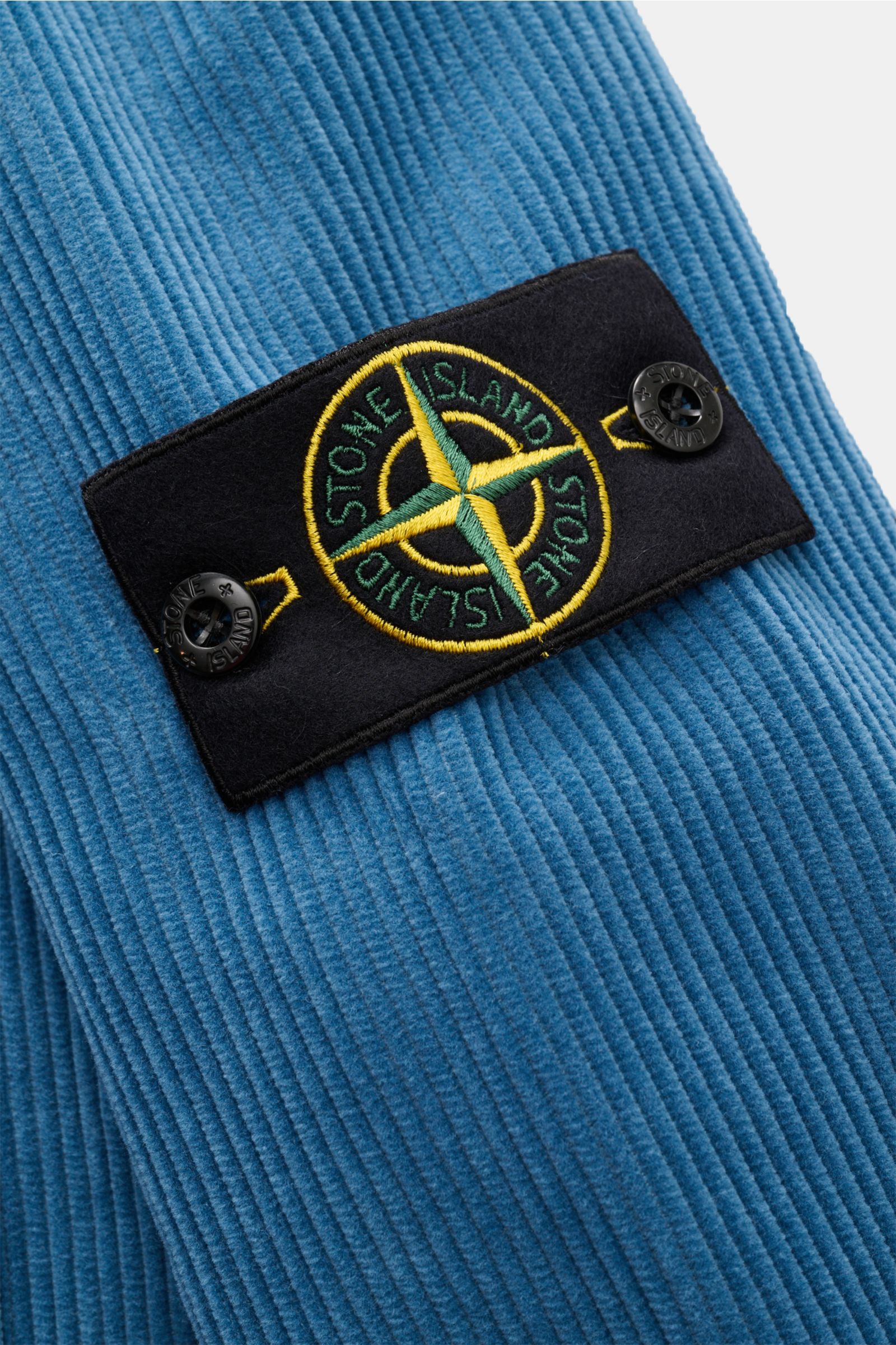 Stone Island Cord Overshirt 'Organic Cotton Corduroy' rauchblau aus Bio-Baumwoll-Cord, Detailaufnahme des typischen Kompass-Badges am Ärmel.