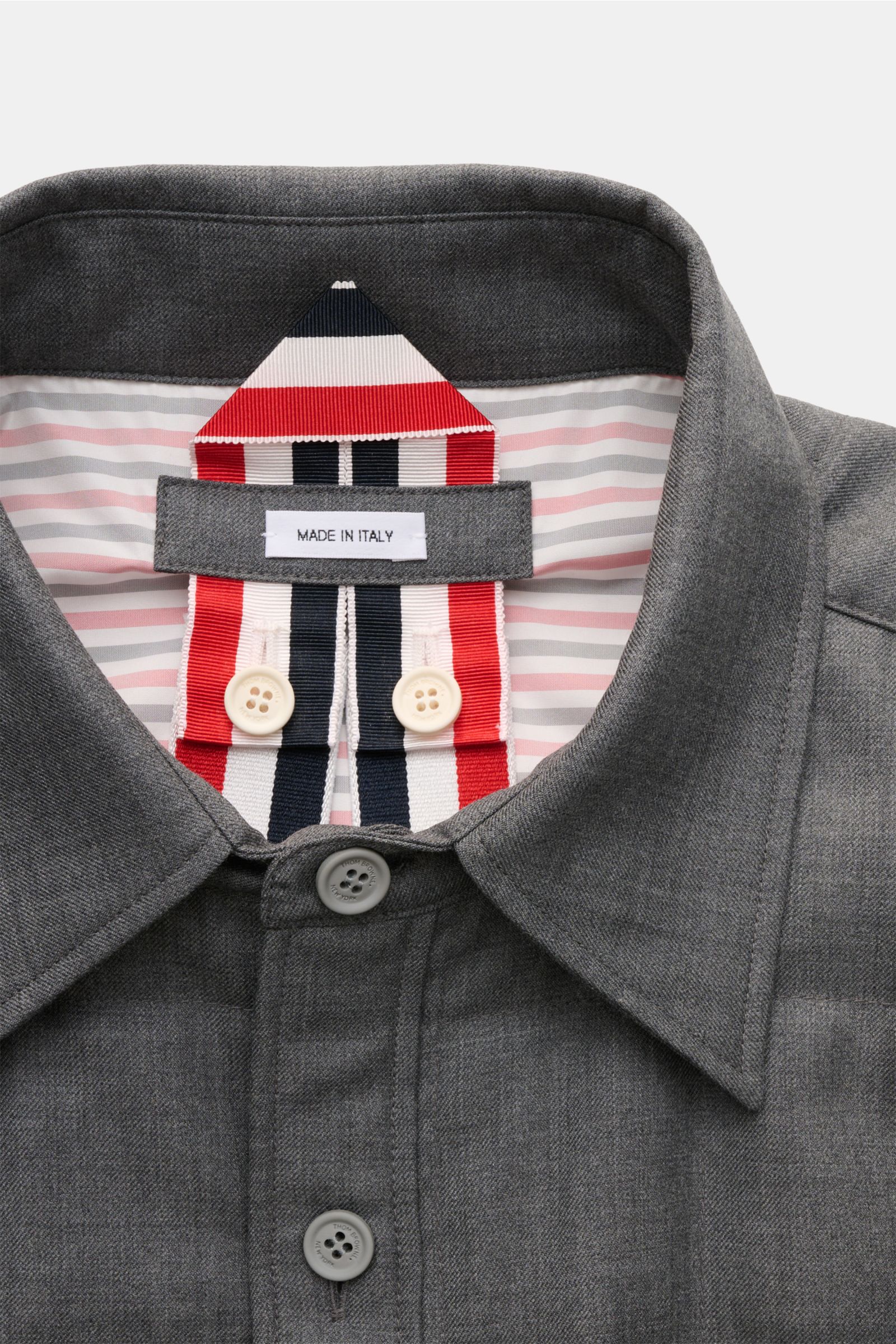 Close-up front view of Thom Browne Daunenjacke dunkelgrau meliert with collar, button placket, and striped inner lining featuring 'Made in Italy' label, showcasing high-quality wool and detailed craftsmanship.

Preppy Jacke von THOM BROWNE: Gefertigt a