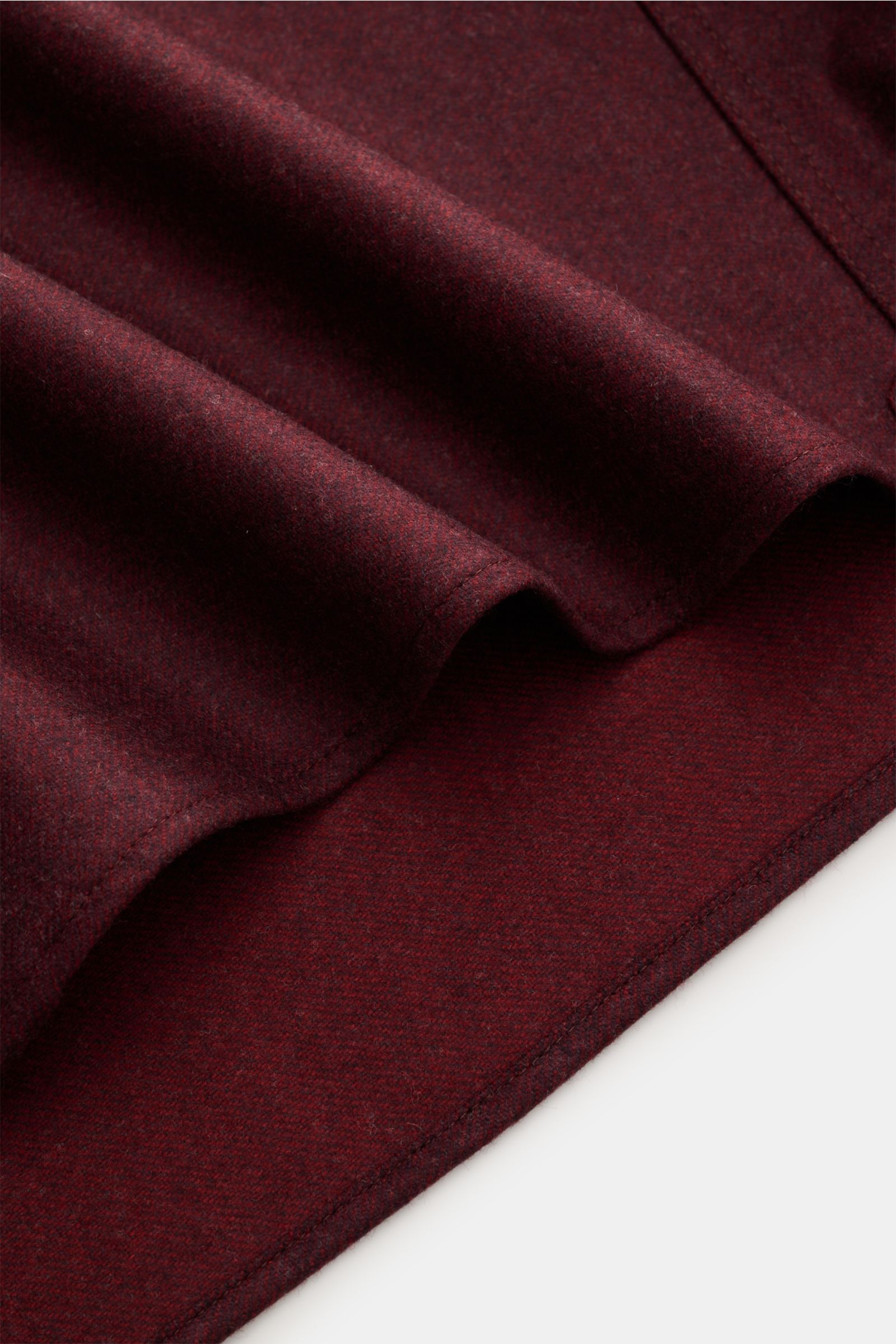 Dark red close-up of fabric texture and edge, showing fine wool material of Brunello Cucinelli Overshirt dunkelgrau meliert from a top-down perspective. Dieses Overshirt aus reiner, softer Wolle von BRUNELLO CUCINELLI ist ein perfektes Layering-Piece f