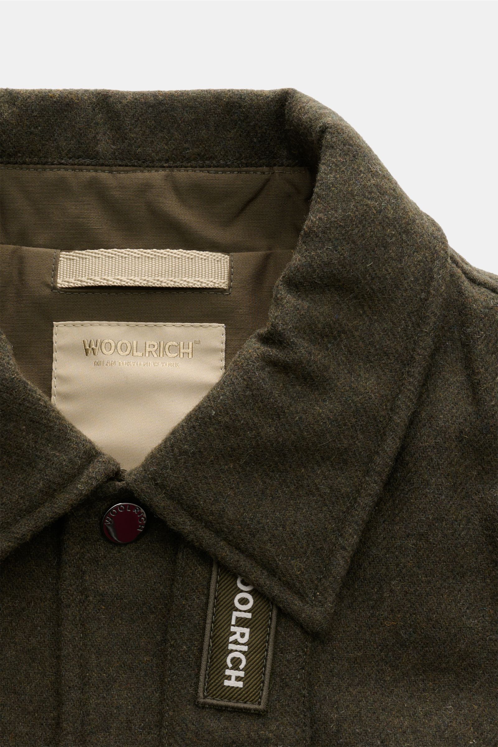 Nahaufnahme der Woolrich Daunenjacke dark olive von oben, zeigt Woll-Microfaser-Mix, leichten Stehkragen und Druckknopf.