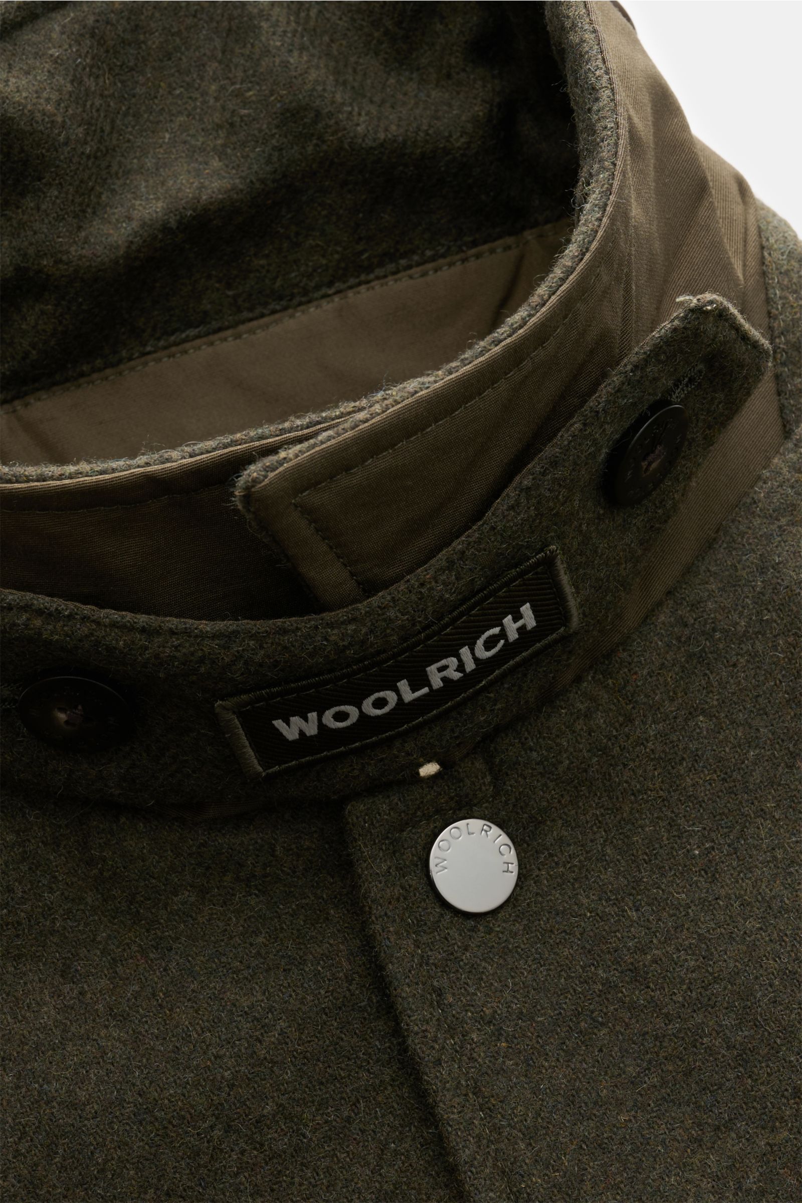 Nahaufnahme der Woolrich Daunenjacke dark olive am Kragen mit Druckknopf, Woll-Microfaser-Mix, Slim Fit und variabelm Kragen.