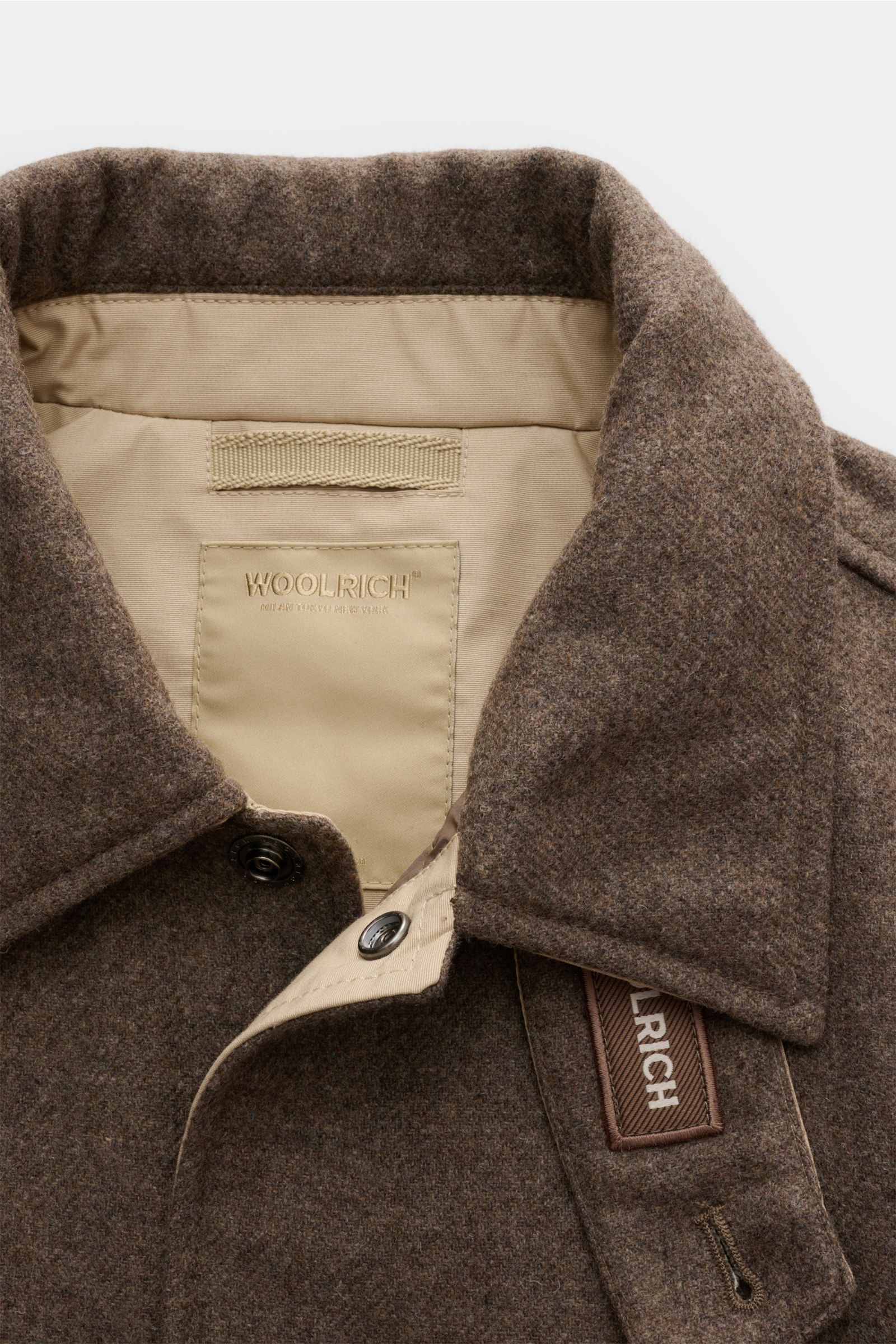 Woolrich Daunenjacke taupe aus Wolle und Microfaser, Slim Fit mit leichter Daunenfüllung, Druckknopfleiste, variabler Kragen, schräge Taschen, Knopfärmeln, Taillenweite, gesteppter Futterstoff und zwei Innentaschen, Nahaufnahme von oben.