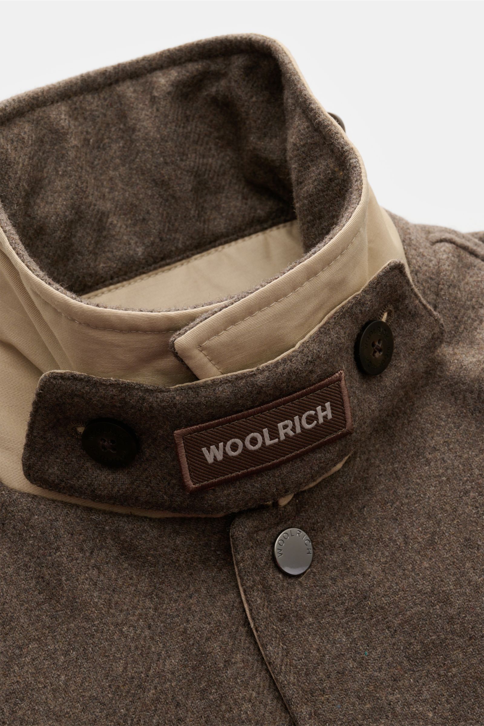 Nahaufnahme der Woolrich Daunenjacke taupe aus Wolle und Microfaser mit Slim Fit, Druckknopfleiste, variablem Kragen mit Knopfriegel, aufgenommen von oben.