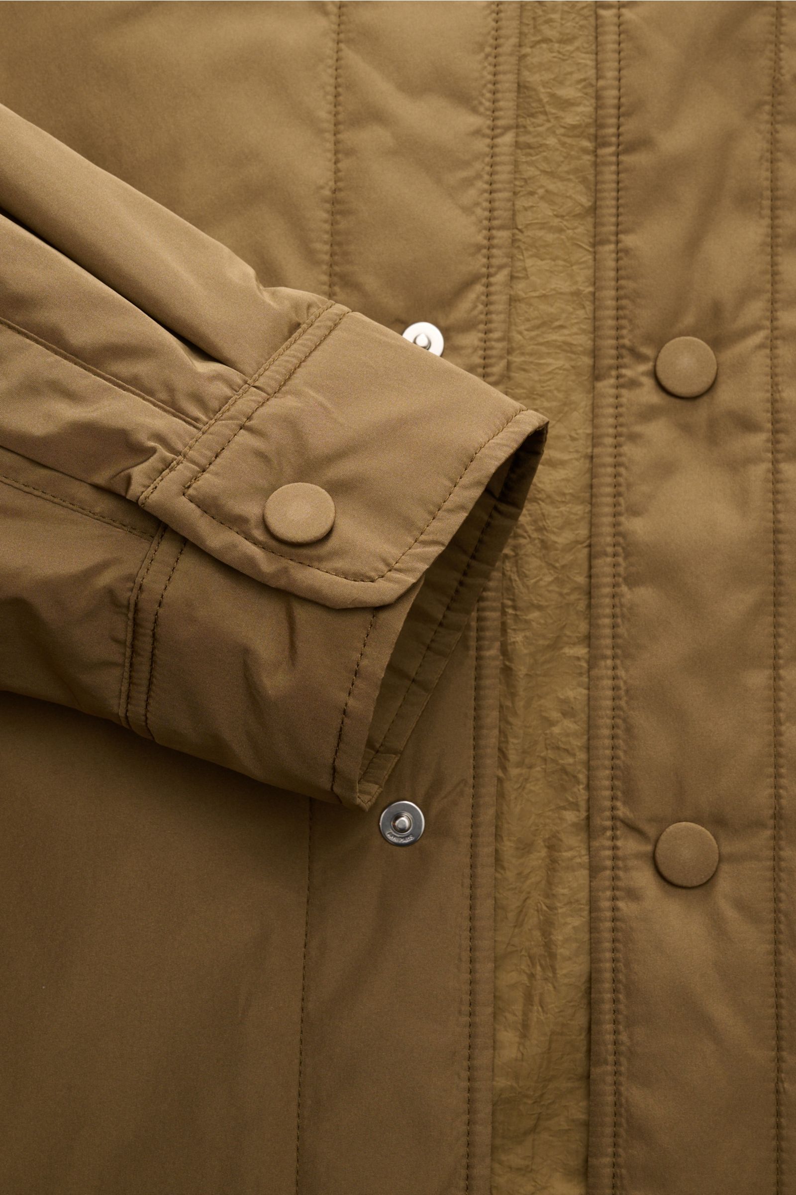 Nahaufnahme des Ami Paris Overshirt graubraun von schräg oben, zeigt sportlich-lässigen Ärmel mit Druckknopf, glatte Microfaser.