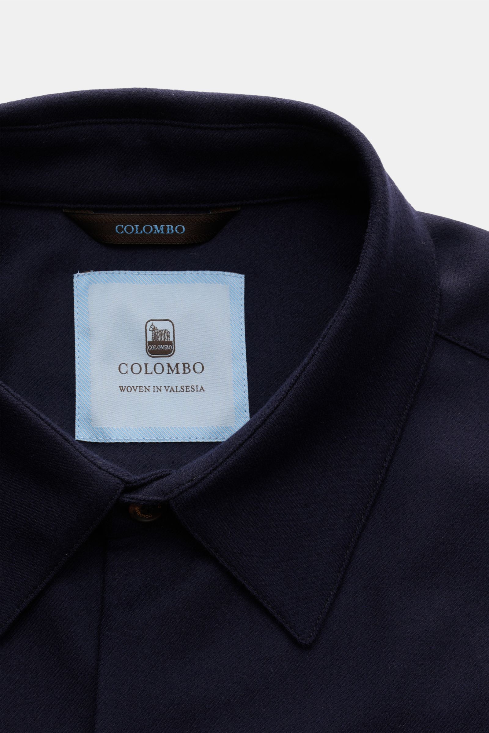 Close-up front view of the Colombo Overshirt navy showing the turn-down collar, six-button placket, and label. Finest wool with microfibre, slightly elasticated fabric, very soft feel, slim fit, concealed pockets in the side seam, classic barrel cuffs, un