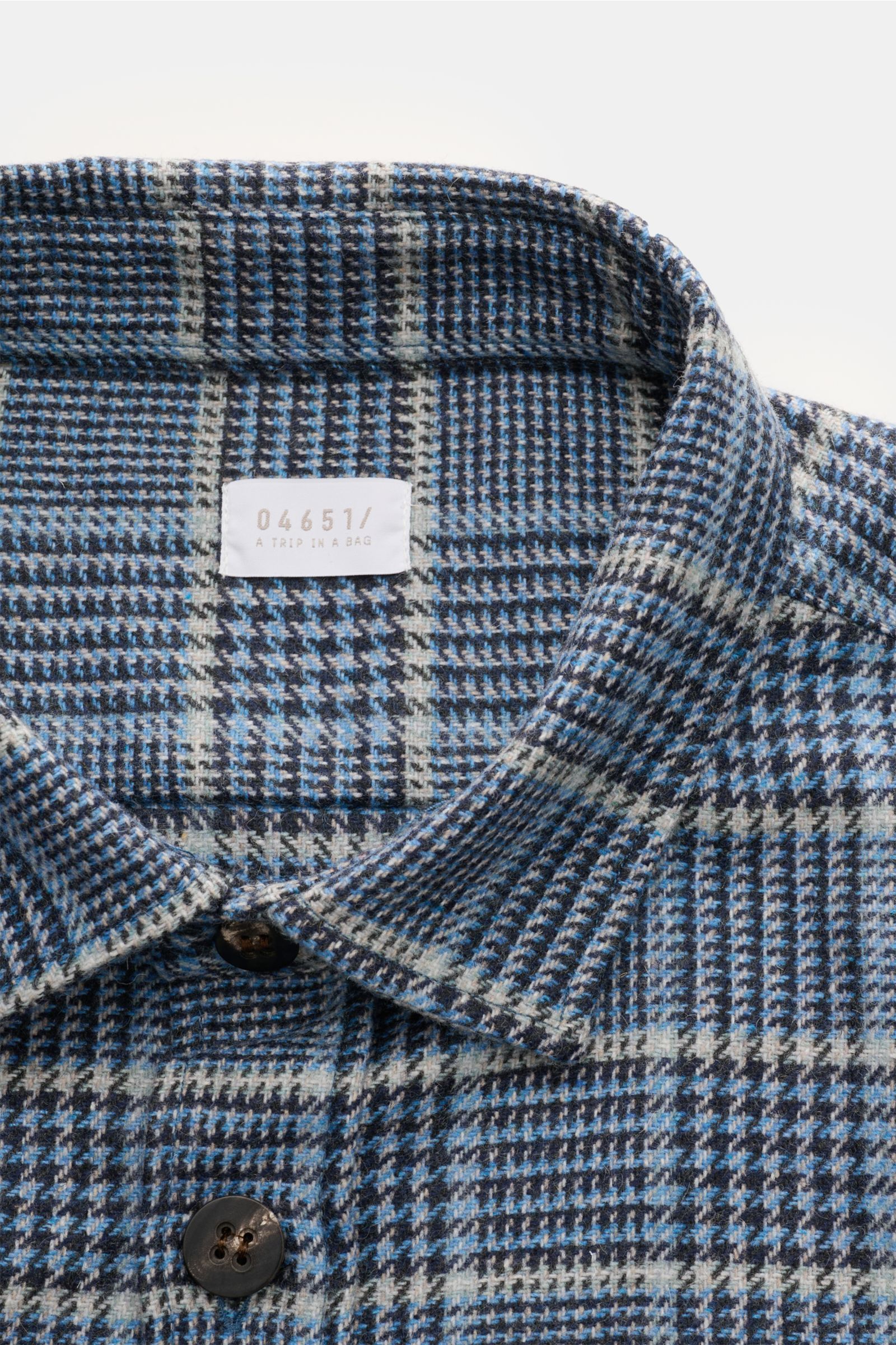 Nahaufnahme von Kragen und Knopfleiste des 04651/ A trip in a bag Overshirt schwarz/blau/hellgrau kariert aus leichtem Woll-Mix mit Glencheck.