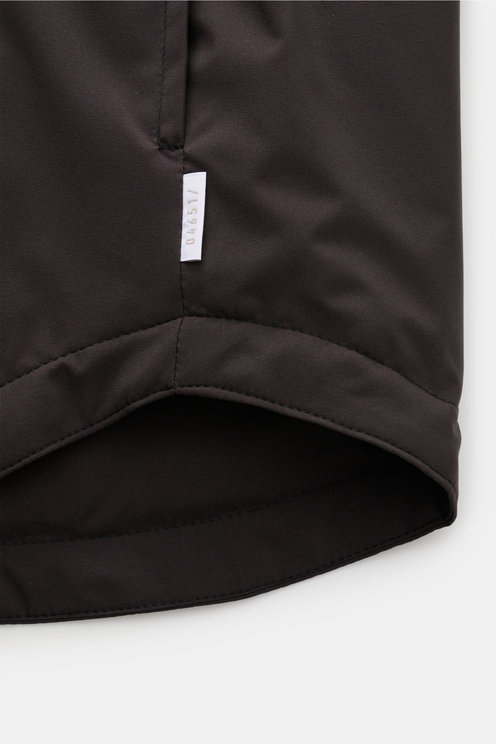 04651/ A trip in a bag Overshirt 'Travel' dunkelbraun, Detailansicht Saum mit Label, superleicht, wind- und wasserabweisend, wattiert, Slim Fit.