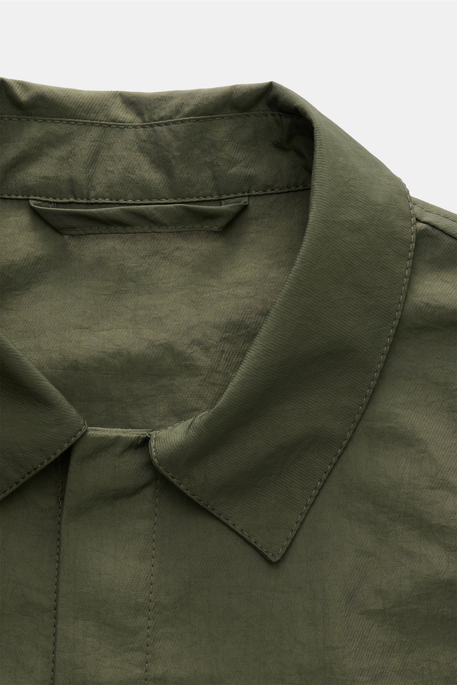 Close-up front view of the collar and snap button placket of the 04651/ A trip in a bag Overshirt 'Travel Jacket' olive in high-quality microfibre.

This season, enhance your outerwear with a practical layer in the form of the super lightweight overshi
