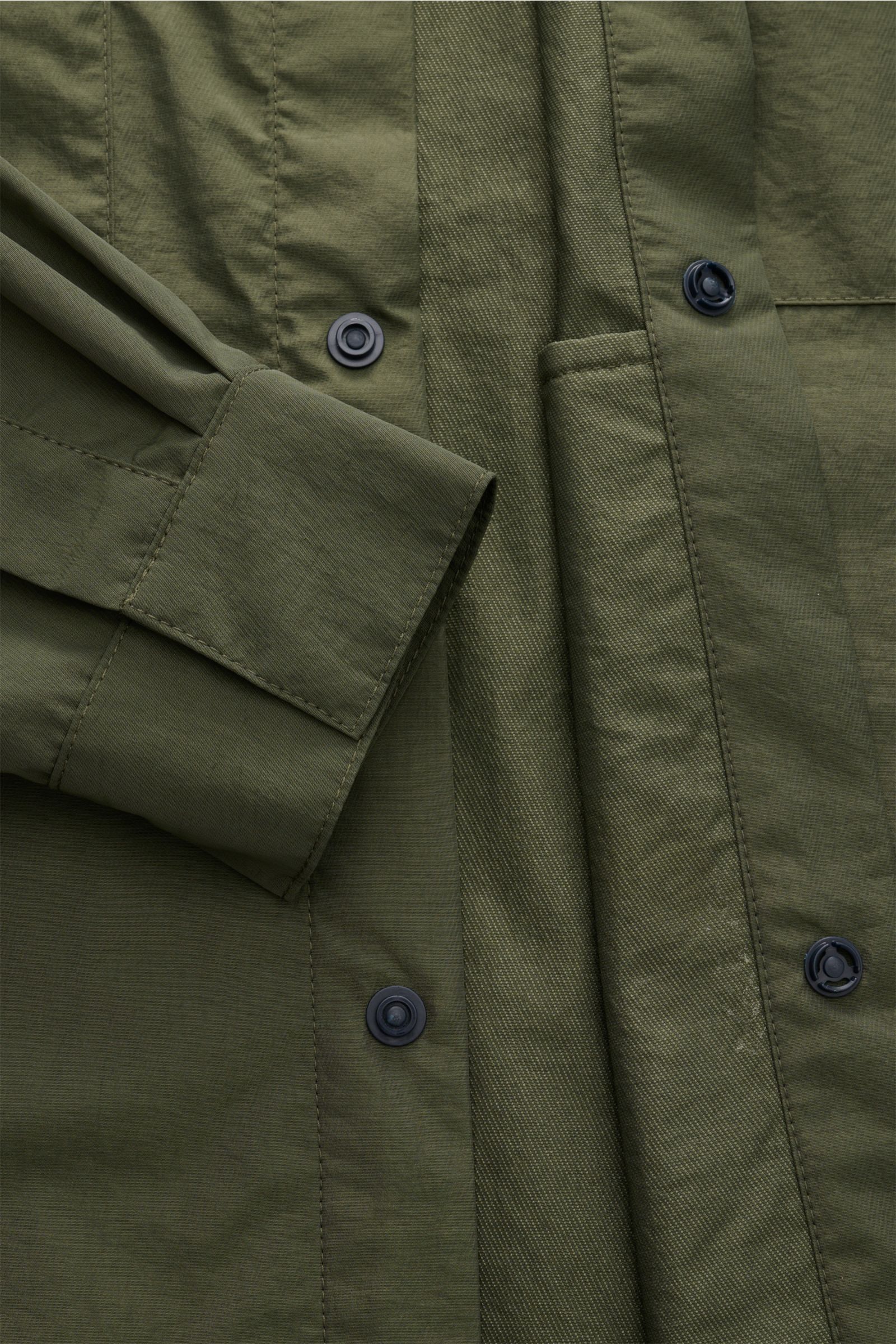 Close-up front view of 04651/ A trip in a bag Overshirt 'Travel Jacket' olive showing snap button placket and cuff details.

This season, enhance your outerwear with a practical layer in the form of the super lightweight overshirt 'Travel Jacket' by 04