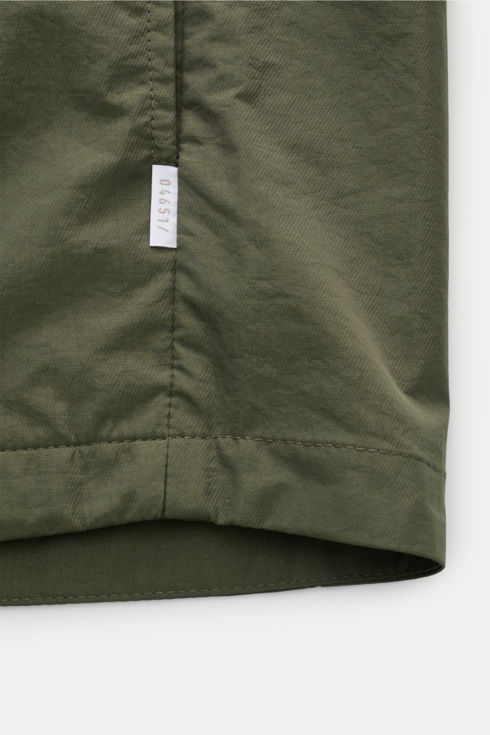 Close-up of the hem and side seam of the 04651/ A trip in a bag Overshirt 'Travel Jacket' olive, showing fabric texture and label.

This season, enhance your outerwear with a practical layer in the form of the super lightweight overshirt 'Travel Jacket