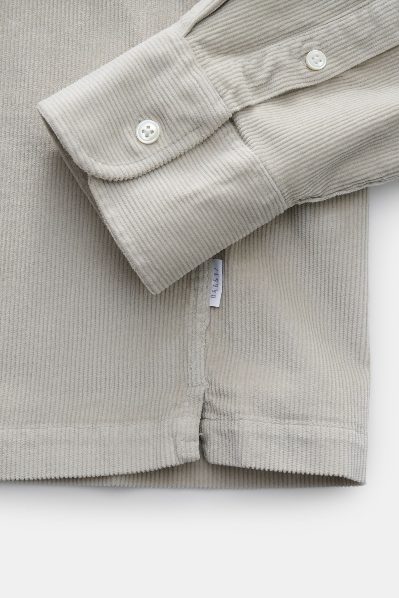 Nahaufnahme des Saumverlaufs und der Sportmanschette eines beigen 04651/ A trip in a bag Popover-Cordhemd Grandad-Kragen aus Cordstoff.