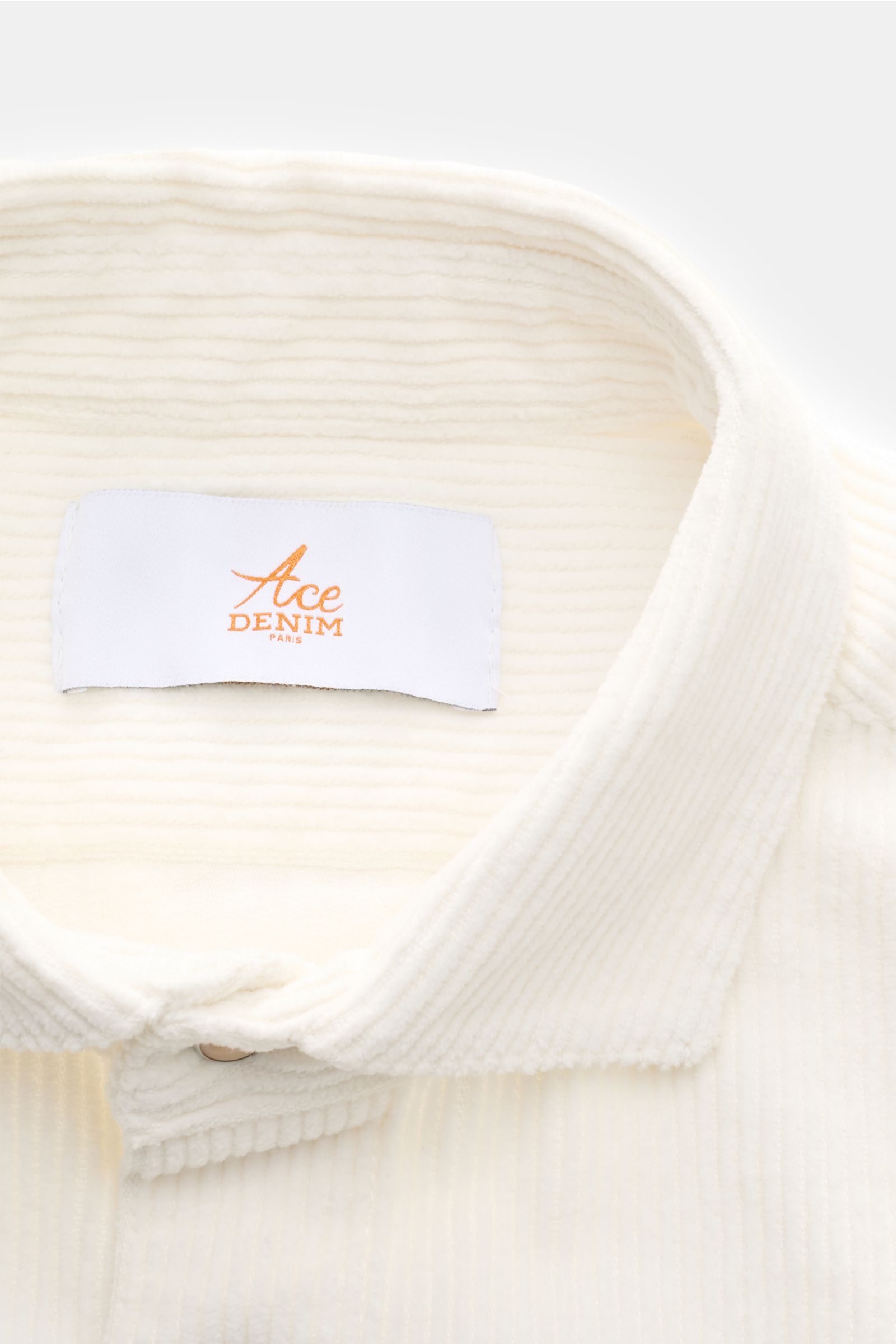 Ace Denim Cord-Overshirt offwhite in Nahaufnahme von oben, Cord aus reiner Baumwolle, weicher Griff, Umlegekragen und Druckknopfleiste sichtbar.