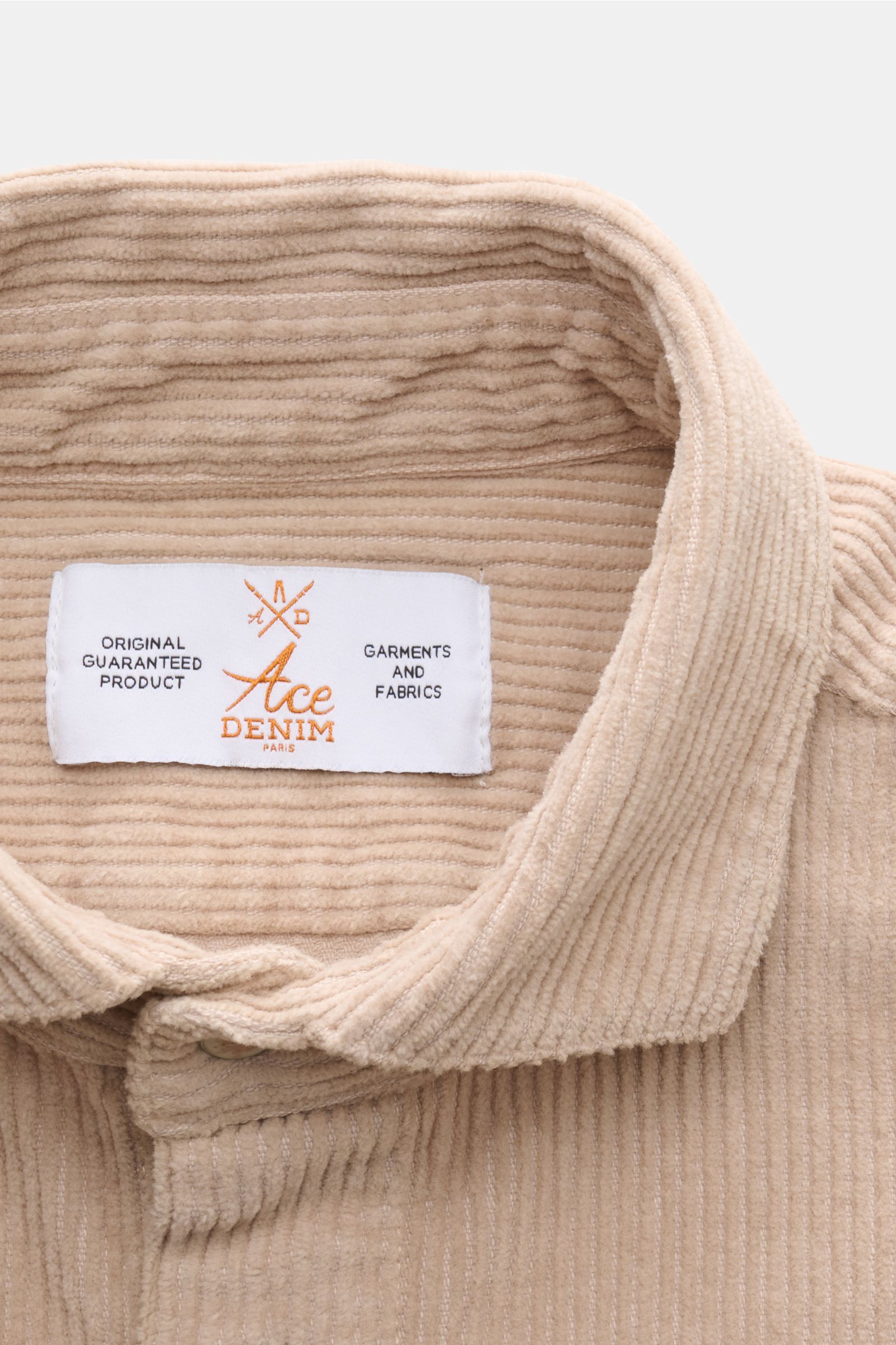 Ace Denim Cord-Overshirt beige in Nahaufnahme von oben, Cord aus reiner Baumwolle, weicher Griff, Umlegekragen mit Markenlabel sichtbar.