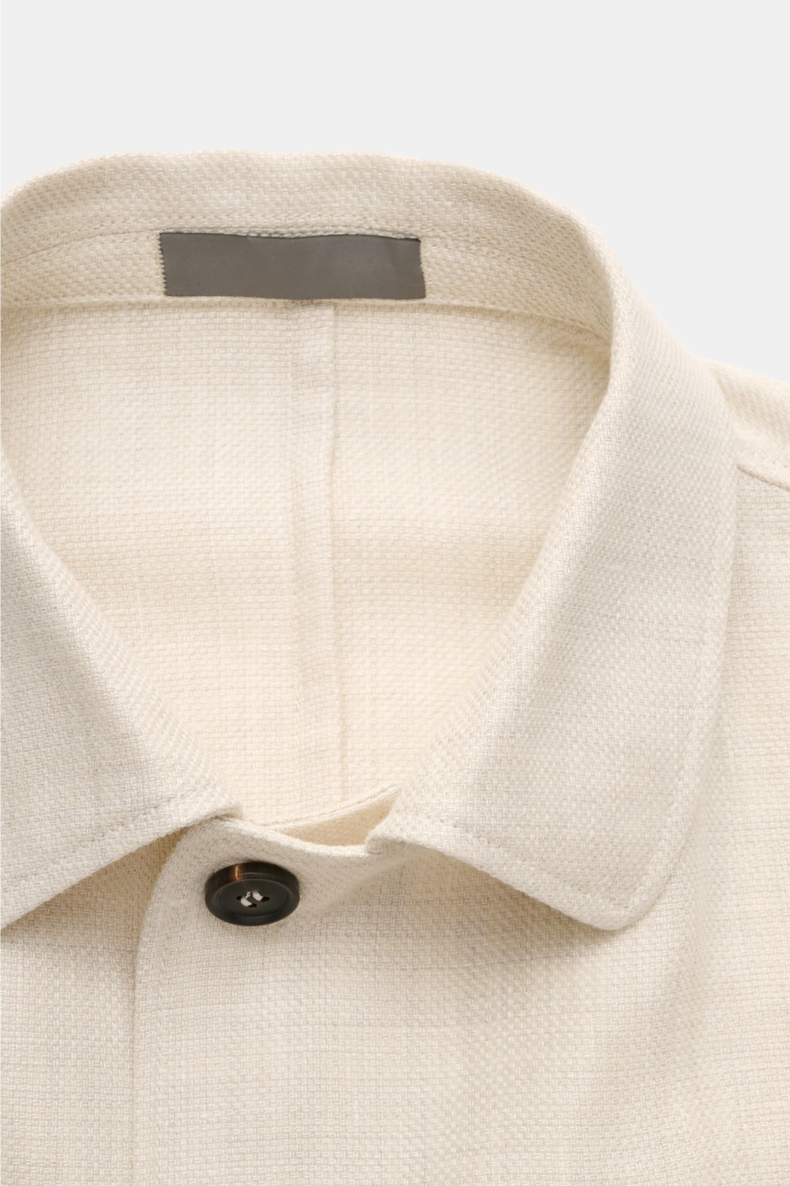 Close-up front view of the collar and top button of the Corneliani Overshirt sand mottled in linen and wool with a textured weave.

This overshirt in linen and wool by CORNELIANI is an elegant shirt-jacket hybrid and enhances a variety of stylish looks