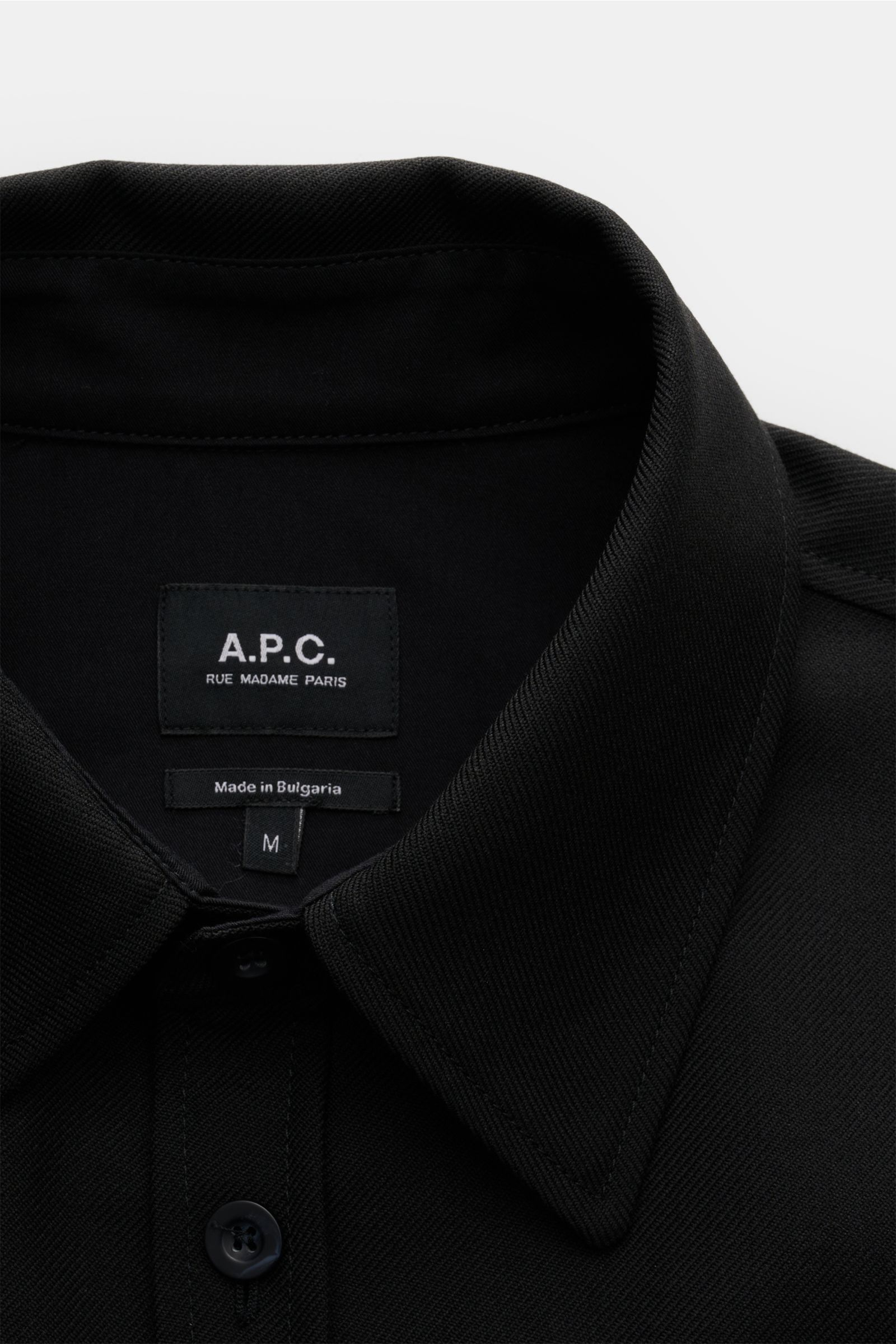 Close-up front view of the collar and top buttons of the A.P.C. Overshirt schwarz, a minimalist essential with clean design. Minimalistisches Essential: Das Overshirt von A.P.C. überzeugt mit seinem cleanen Design und wird so zum vielseitigen Layering-