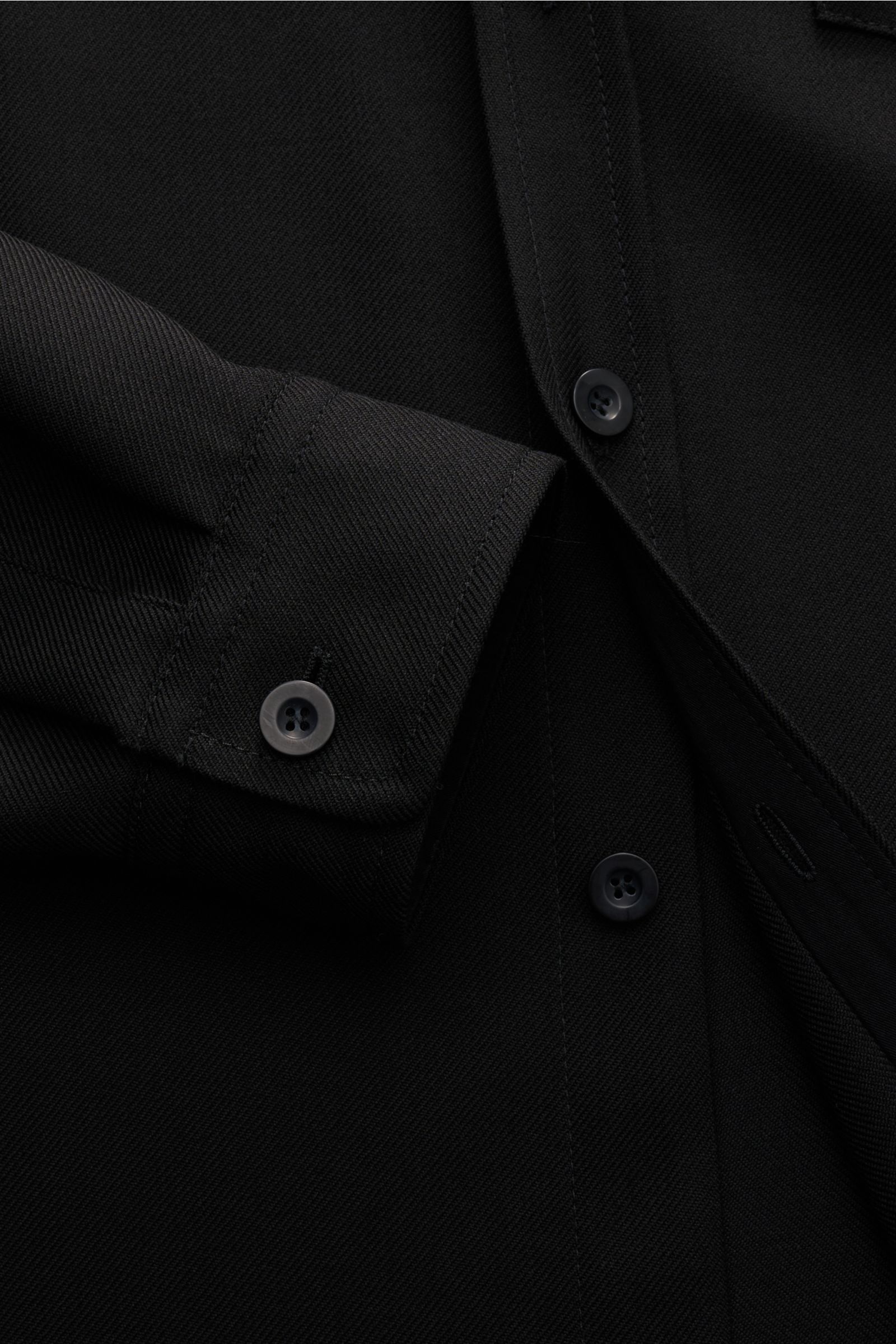 Close-up front view of A.P.C. Overshirt schwarz showing seven-button placket, cuff with button, chest pocket, and wool-microfiber fabric. Minimalist essential with clean design, regular fit, spread collar, and slightly textured quality.