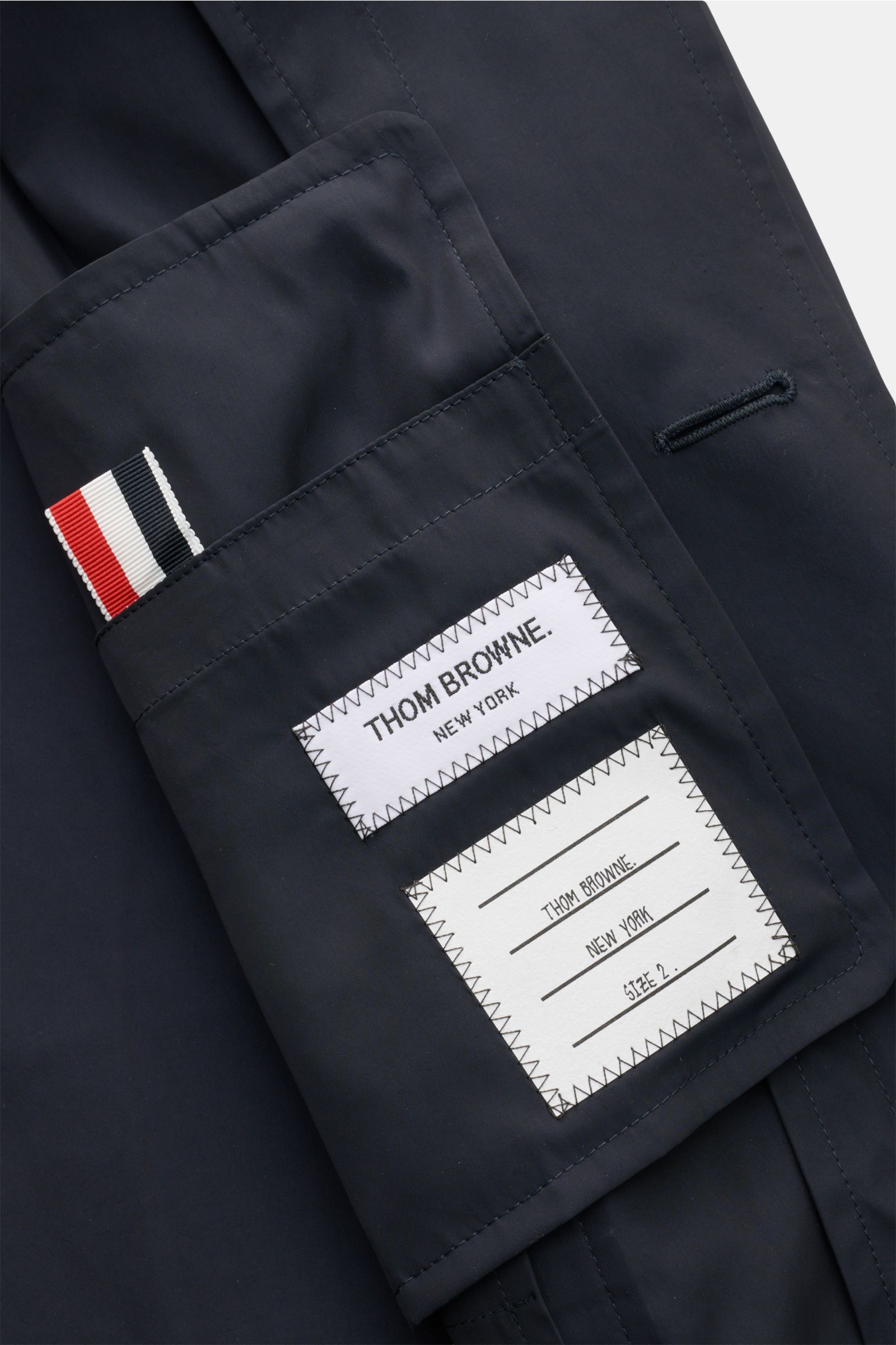 Nahaufnahme des Thom Browne Overshirt navy von innen, zeigt hochwertige Microfaser, glatten Griff, Label und Innentasche.