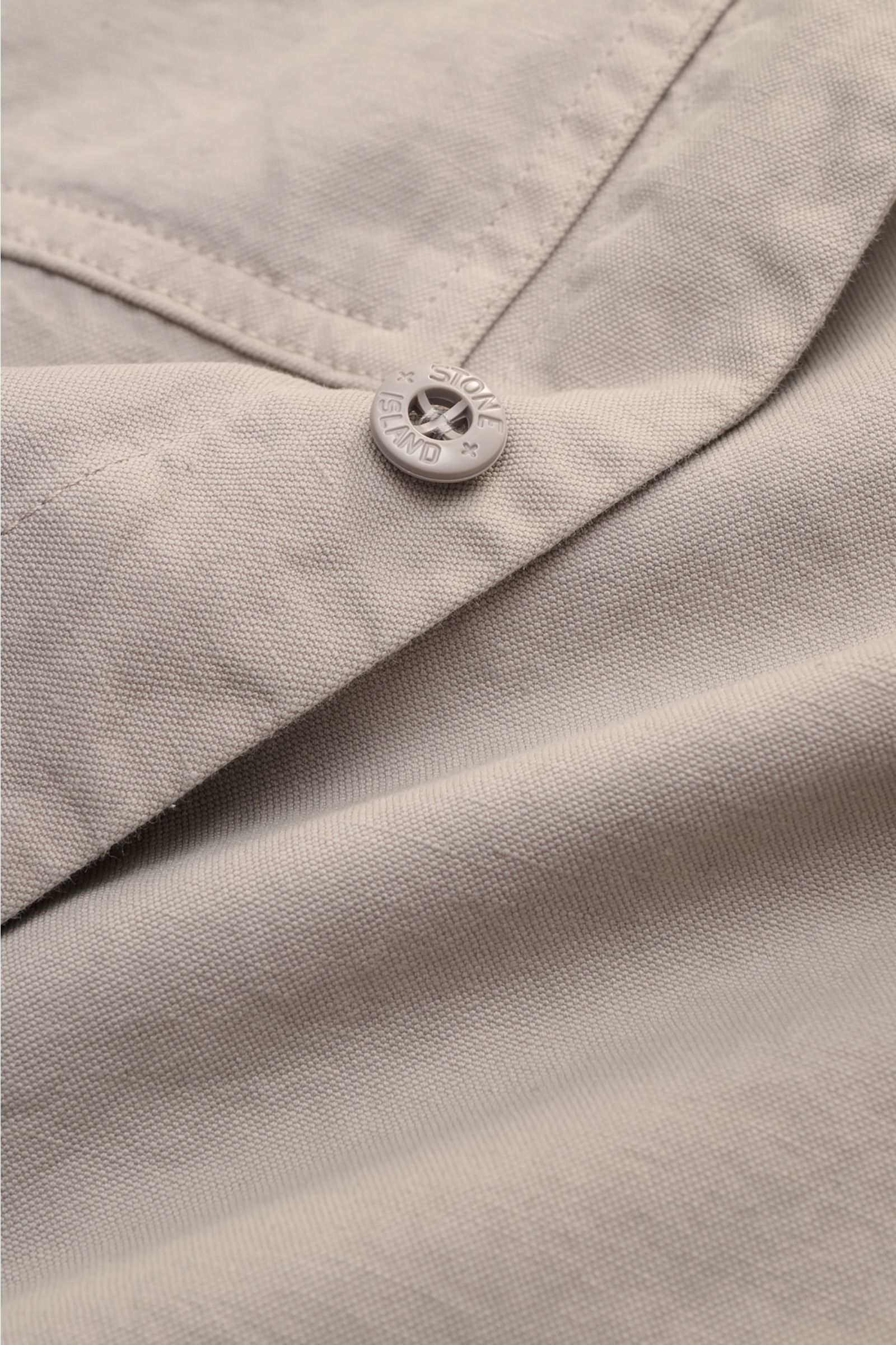 Close-up front view of Stone Island Overshirt 'Ghost' light grey showing cotton-linen fabric, six-button placket, and branded button. Timeless layering piece: This overshirt from the 'Ghost' capsule by STONE ISLAND perfectly enhances casual spring looks. 