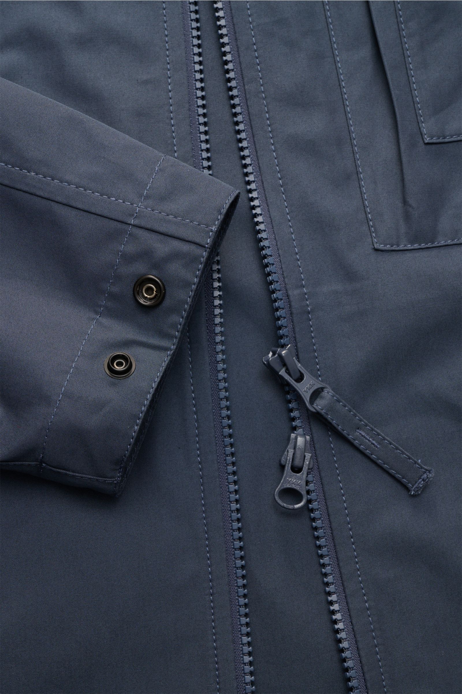 Nahaufnahme des Stone Island Overshirt 'Ghost Piece' graublau aus dichtem Baumwollcanvas, Slim Fit, Zwei-Wege-Reißverschluss, Knopfärmelabschluss.