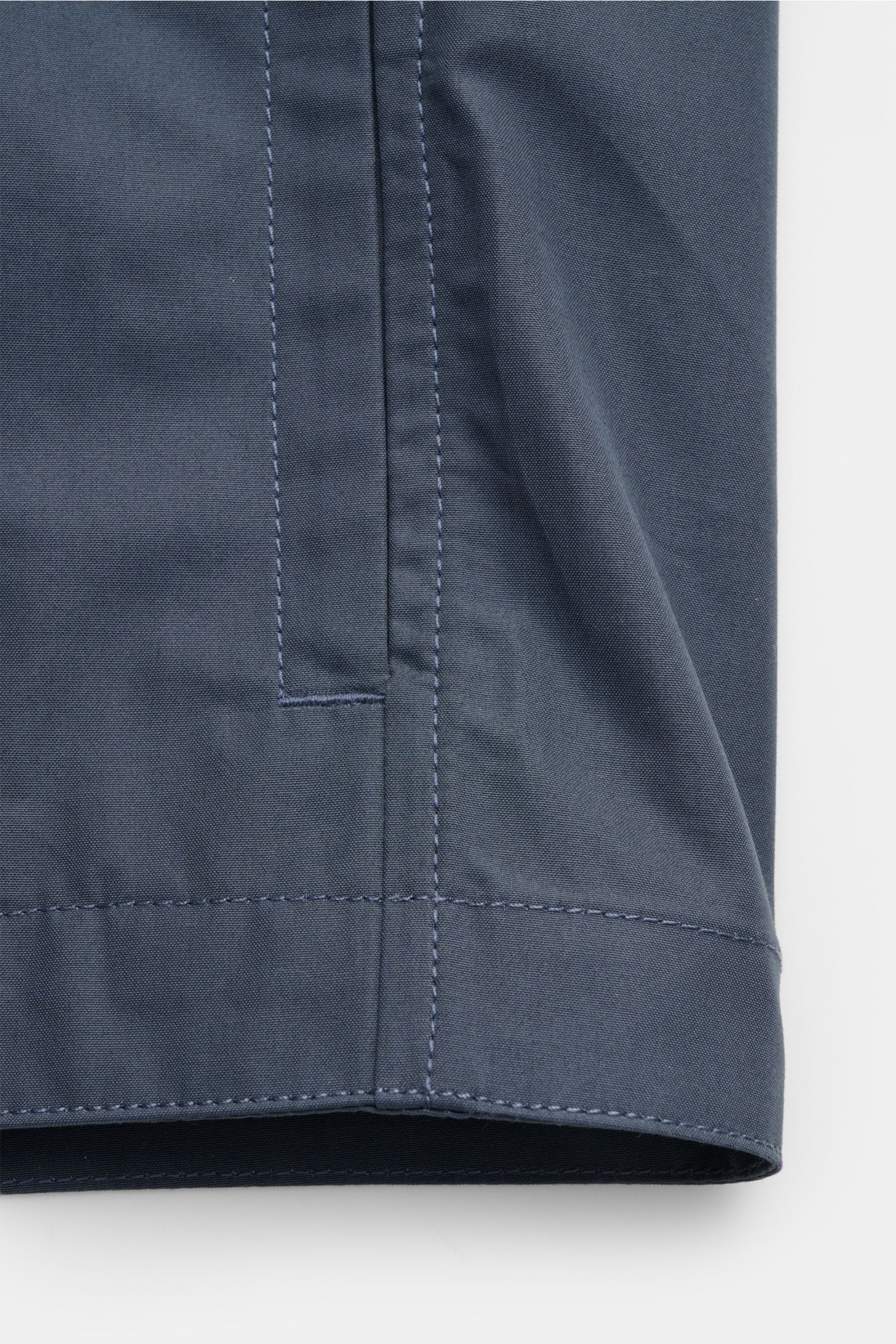 Close-up view of the hem and side seam of the Stone Island Overshirt 'Ghost Piece' graublau, showcasing its smooth pure cotton canvas fabric and detailed stitching. Funktion trifft Komfort: Das STONE ISLAND Overshirt aus der 'Ghost' Capsule wurde aus eine