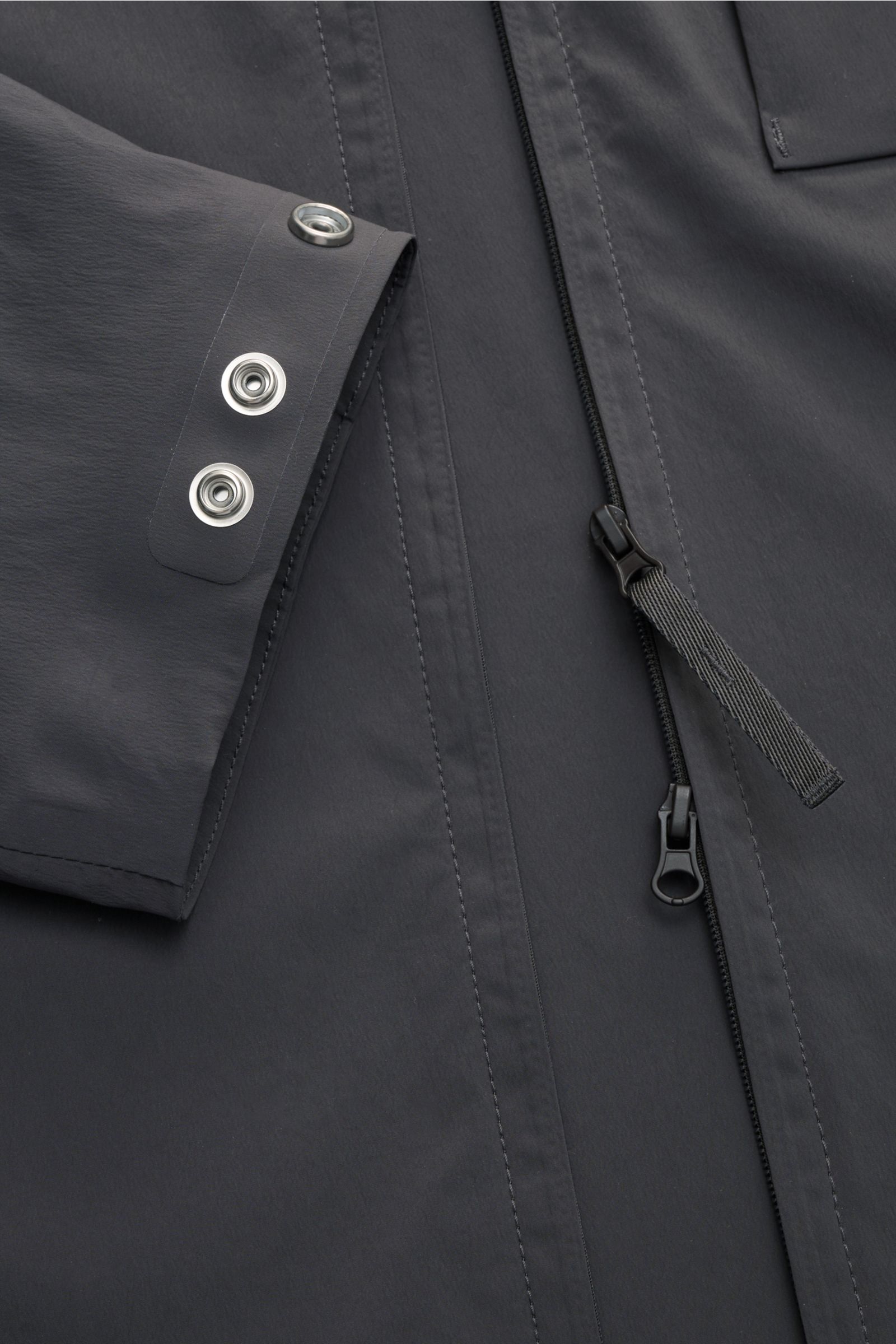 Nahaufnahme der Stone Island Jacke 'Stellina' dunkelgrau aus Microfaser mit glattem Griff, Zwei-Wege-Reißverschluss und Ärmelknöpfen.