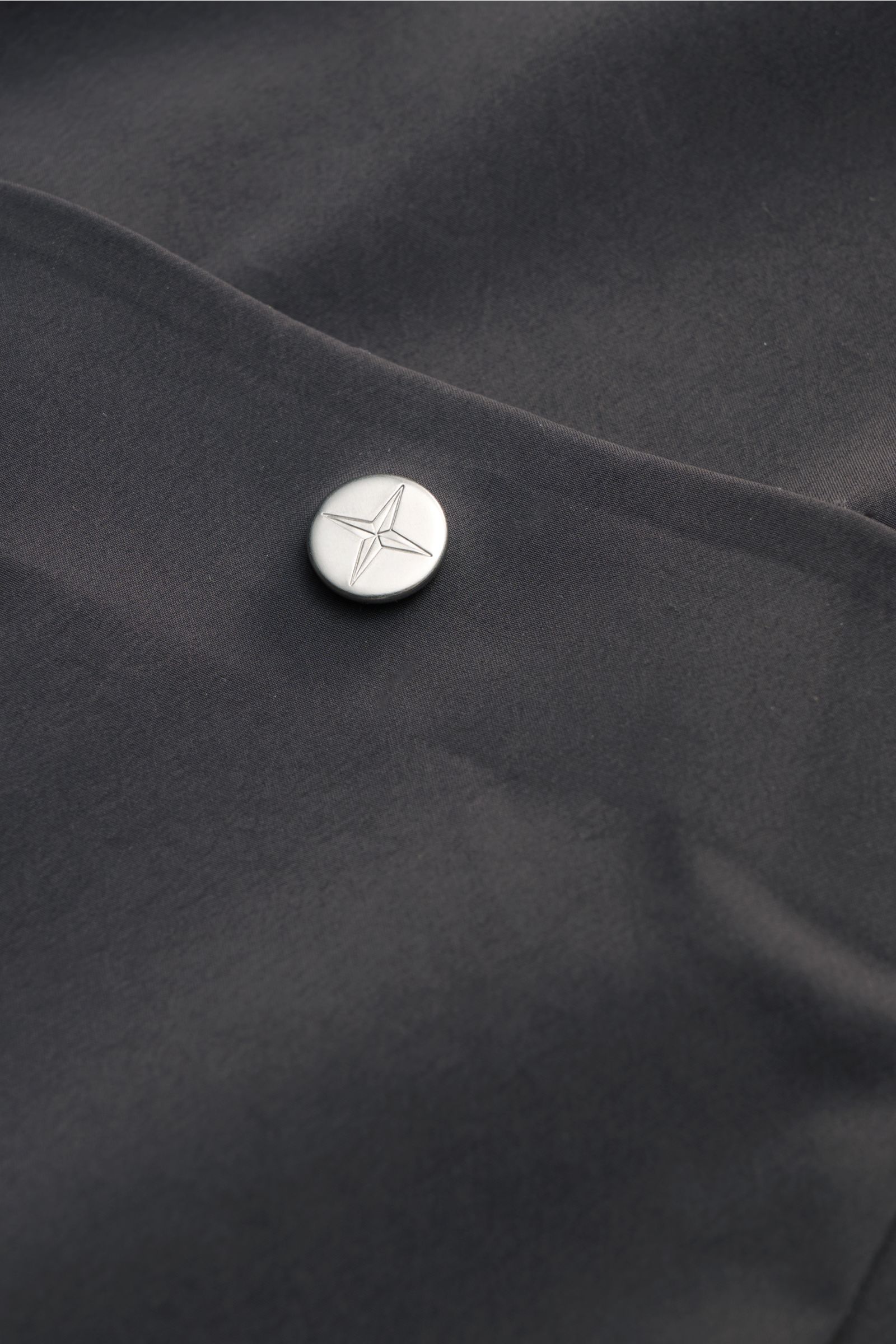Stone Island Jacke 'Stellina' dunkelgrau aus glatter Microfaser mit Knopfdetail der aufgesetzten Brusttasche, Nahaufnahme.
