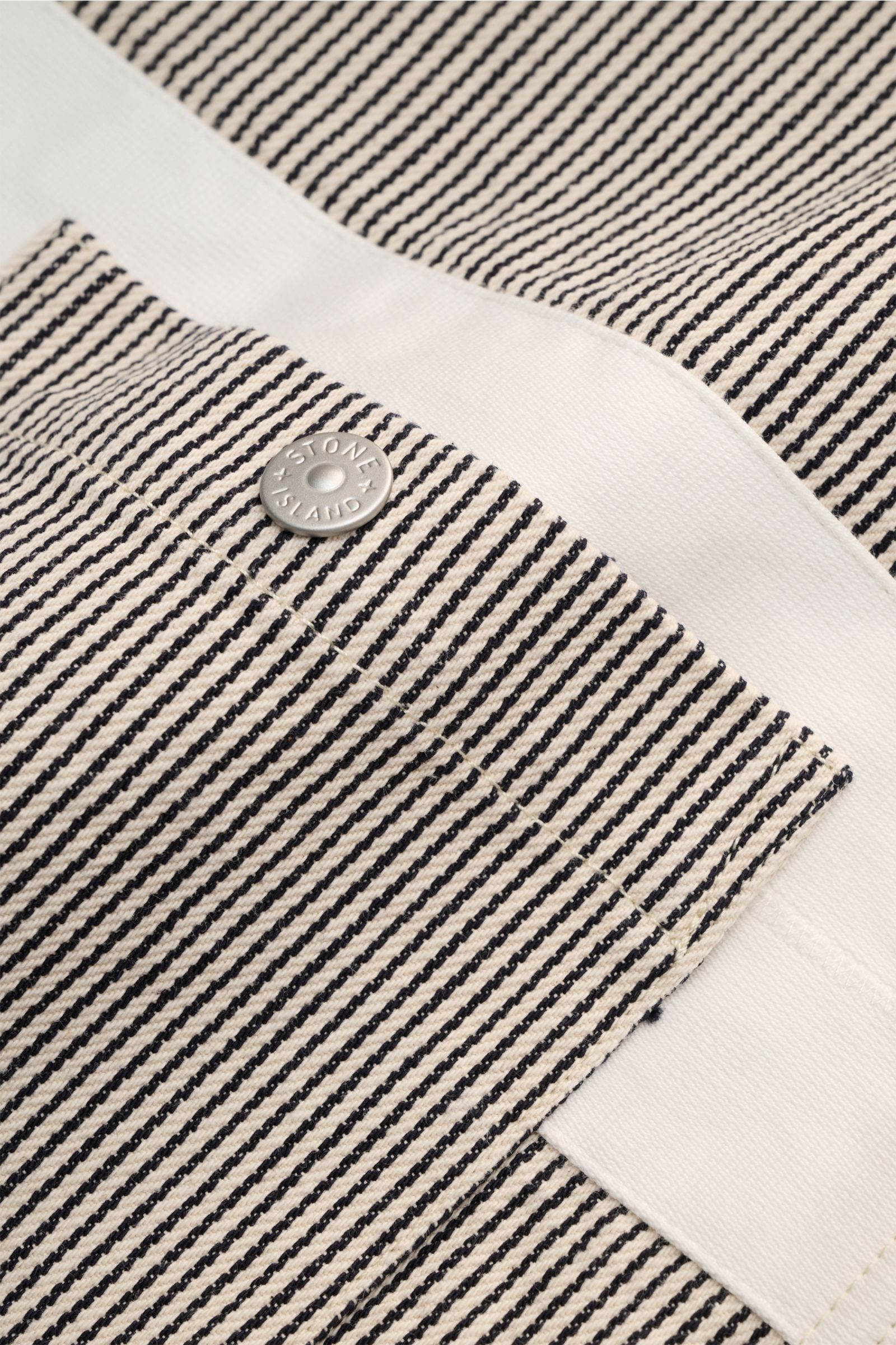 Close-up front view of Stone Island Jacke 'Marina' navy/beige gestreift showing striped cotton fabric, chest pocket with logo button. Light outerwear with maritime character, regular fit, robust two-way zipper, hood with drawstring, button cuffs, adjustab