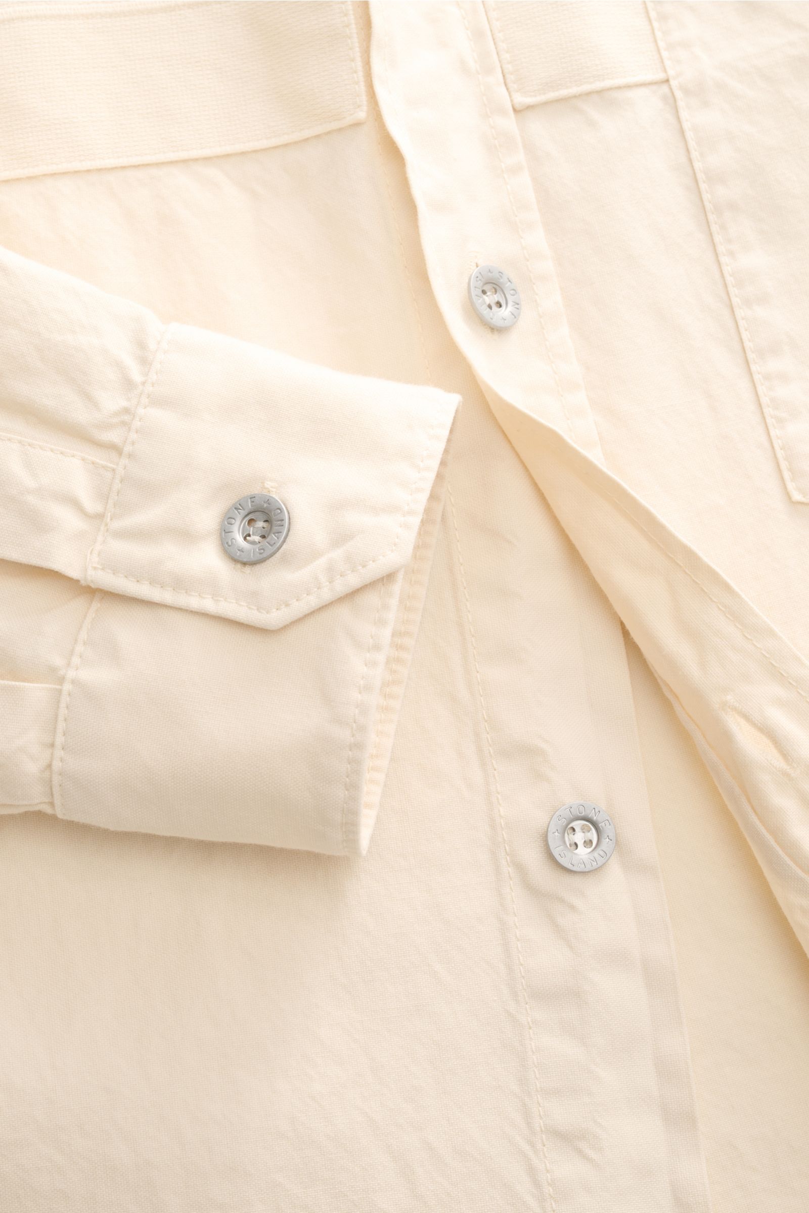 Close-up front view of the Stone Island Overshirt 'Marina' creme, showcasing its six-button placket, cuff with button, chest pocket, and Panama-weave cotton fabric with soft texture. Maritimes Layering-Piece: Das Overshirt aus der STONE ISLAND 'Marina' Ca