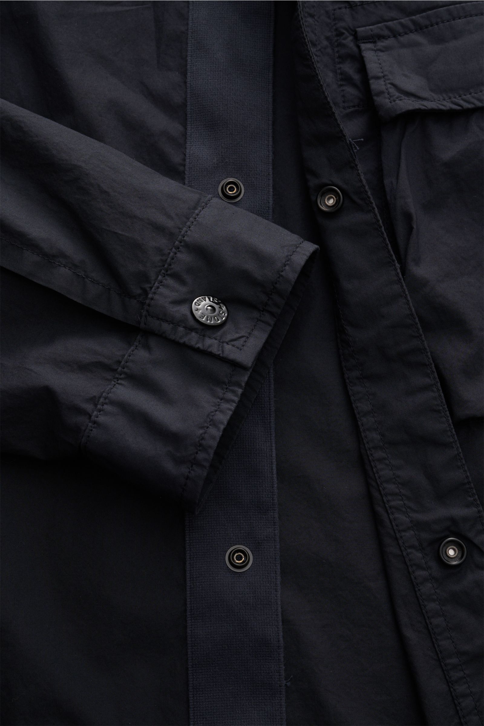 Close-up front view of Stone Island Overshirt navy showing concealed snap button placket, sleeve cuff with button, and part of chest pocket.

Vielseitiges Essential: Mit seinem zeitlosen Design wird das STONE ISLAND Overshirt in der Frühlingssaison zum
