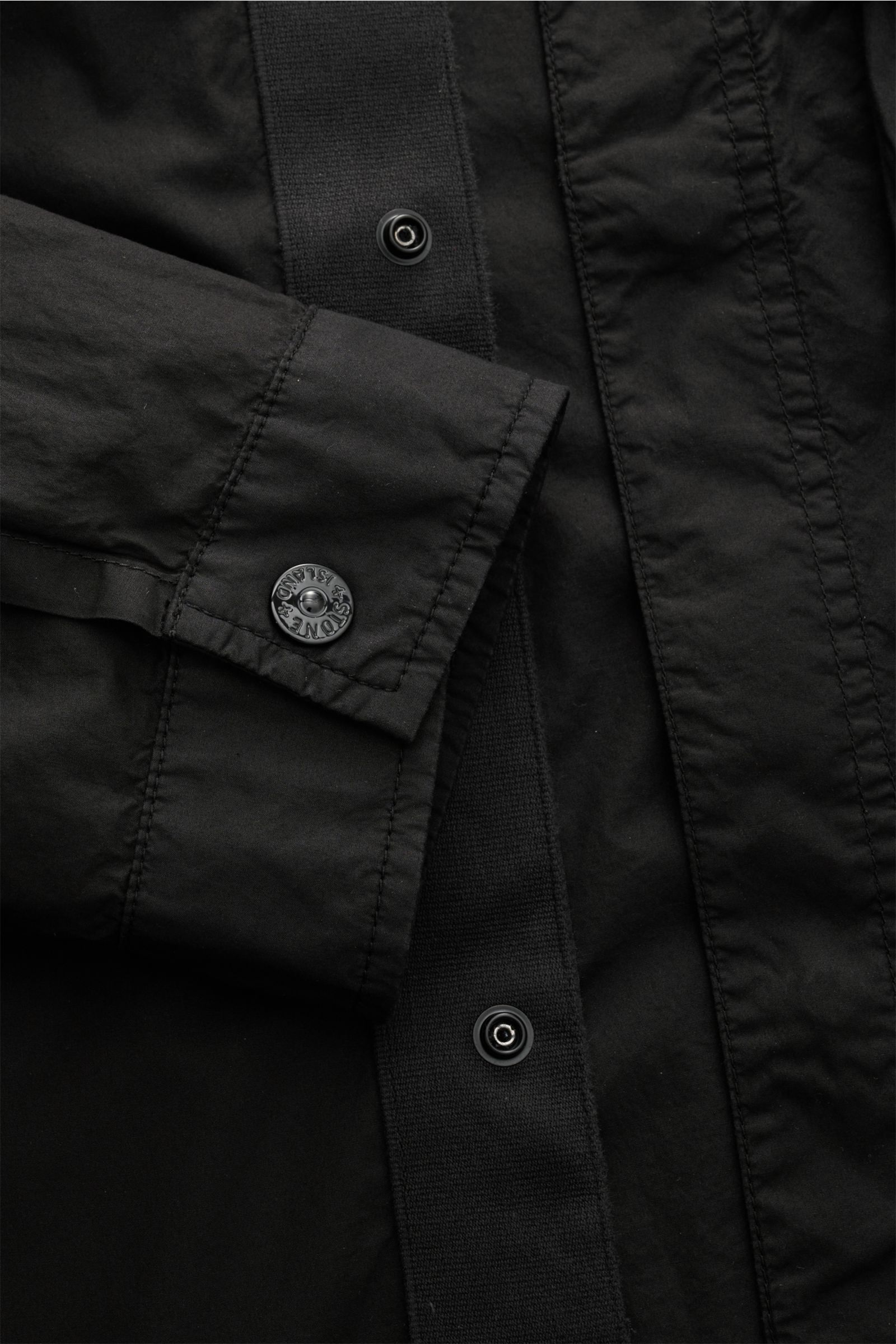 Close-up front view of Stone Island Overshirt schwarz showing elastic cotton fabric, soft touch, slim fit, concealed snap button placket, cuff with button.

Vielseitiges Essential: Mit seinem zeitlosen Design wird das STONE ISLAND Overshirt in der Früh