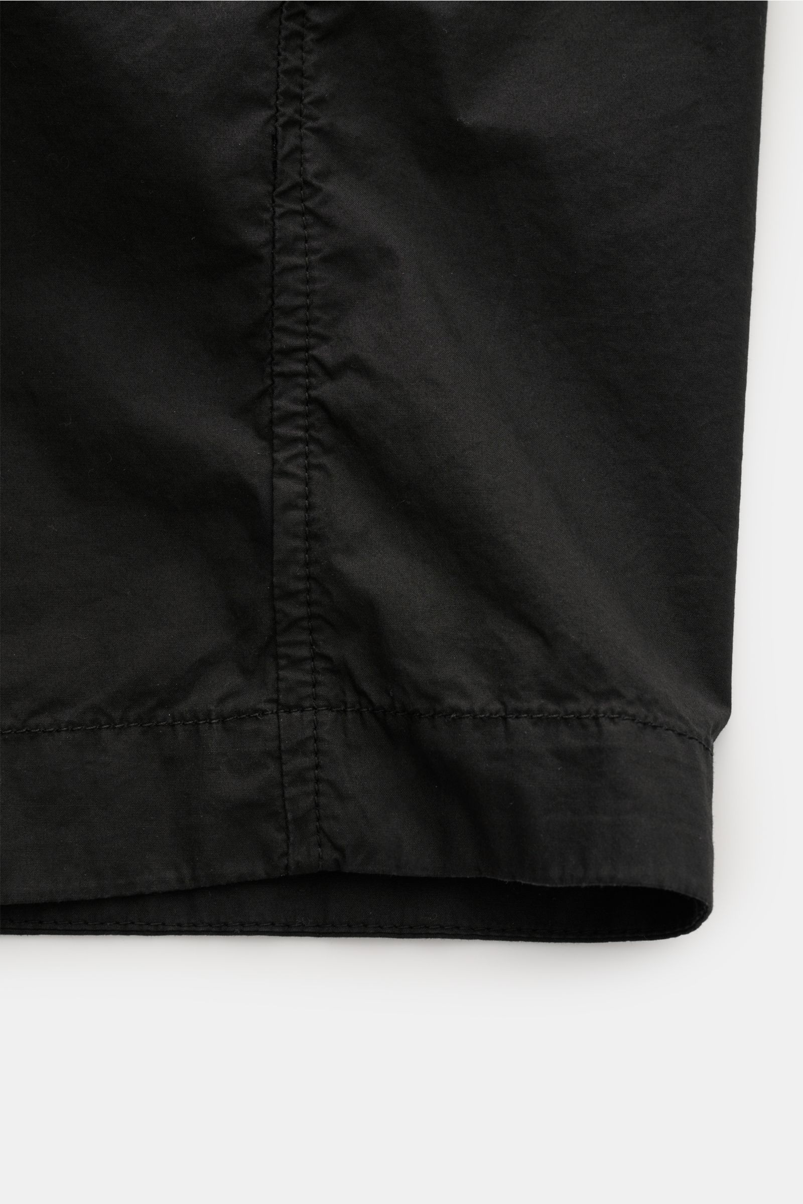 Close-up front lower section of Stone Island Overshirt schwarz, showing elastic cotton fabric with soft texture and detailed stitching.