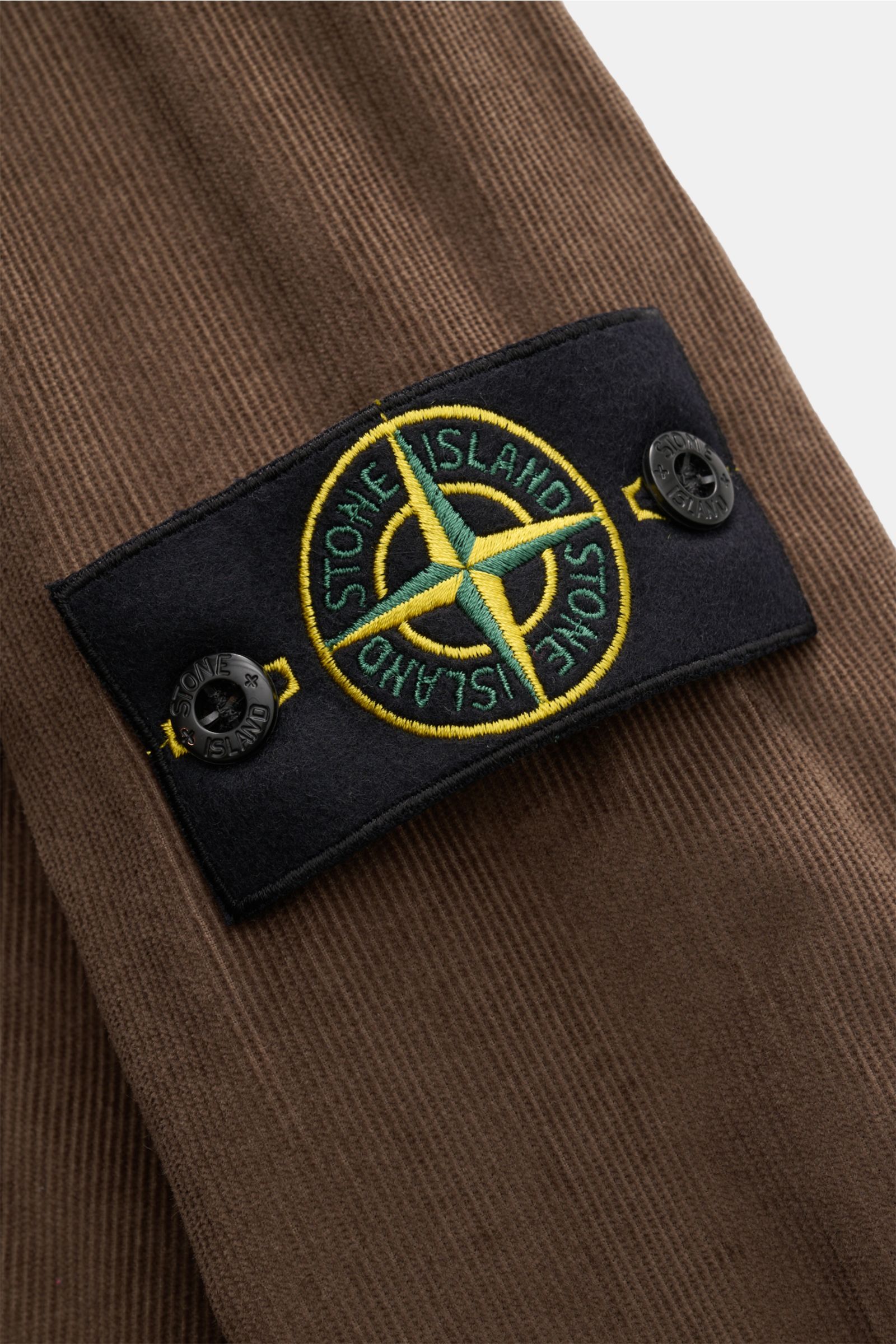 Alt tag (125 characters max): Close-up of the sleeve with the signature compass badge on the brown Stone Island Corduroy overshirt, showing fine texture.

Description:
Sporty and practical – this straight cut overshirt by STONE ISLAND is characterised 