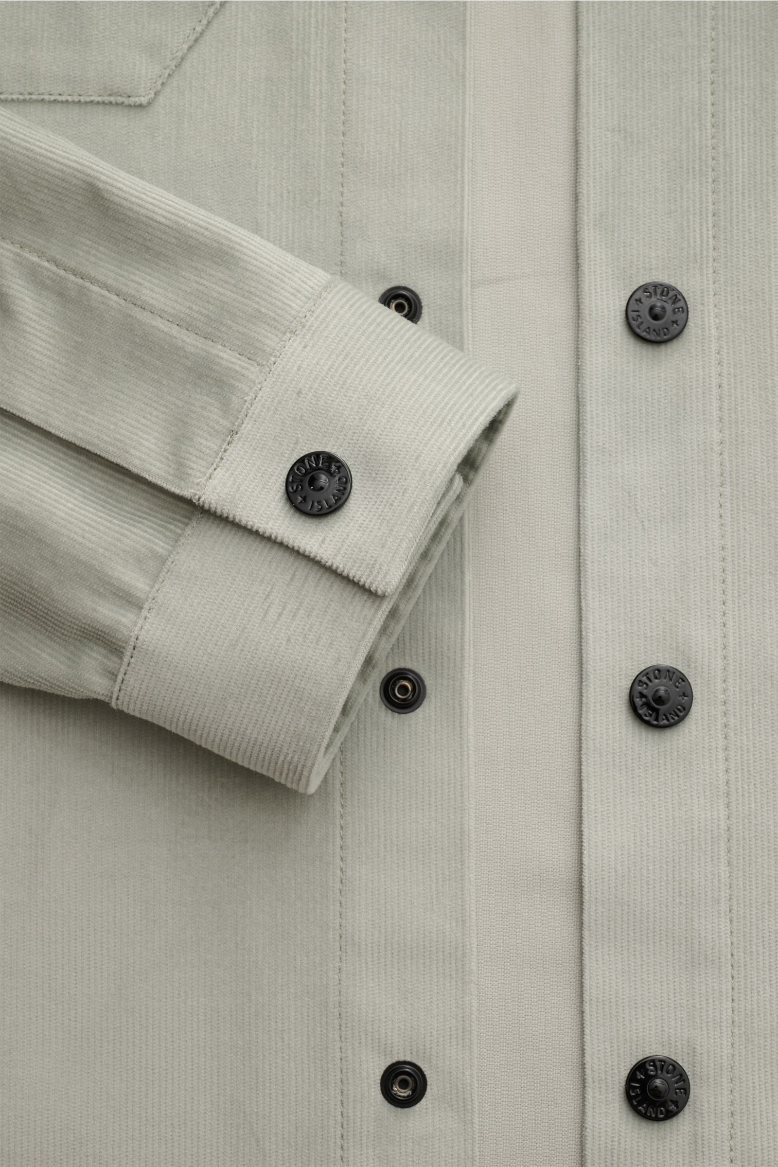 Stone Island Cord Overshirt salbei aus reiner Bio-Baumwolle, Slim Fit, mit Druckknöpfen, Manschetten und Kompass-Badge, Nahaufnahme von vorne.