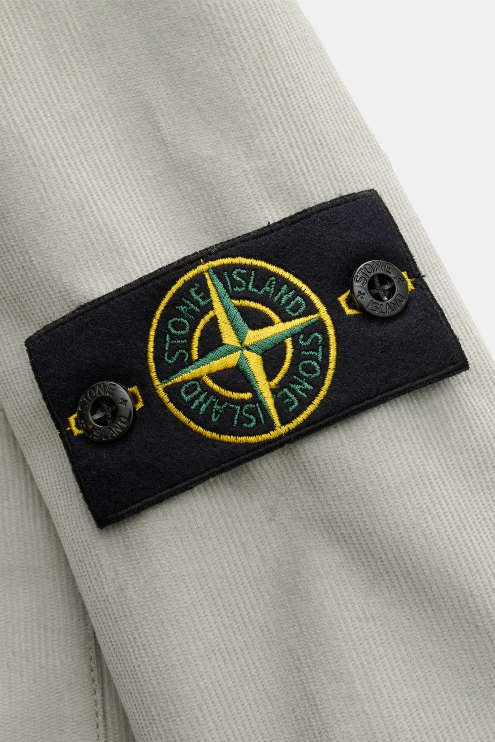 Stone Island Cord Overshirt salbei in Nahaufnahme von Ärmel mit typischem Kompass-Badge, Cord aus reiner Bio-Baumwolle, Slim Fit.