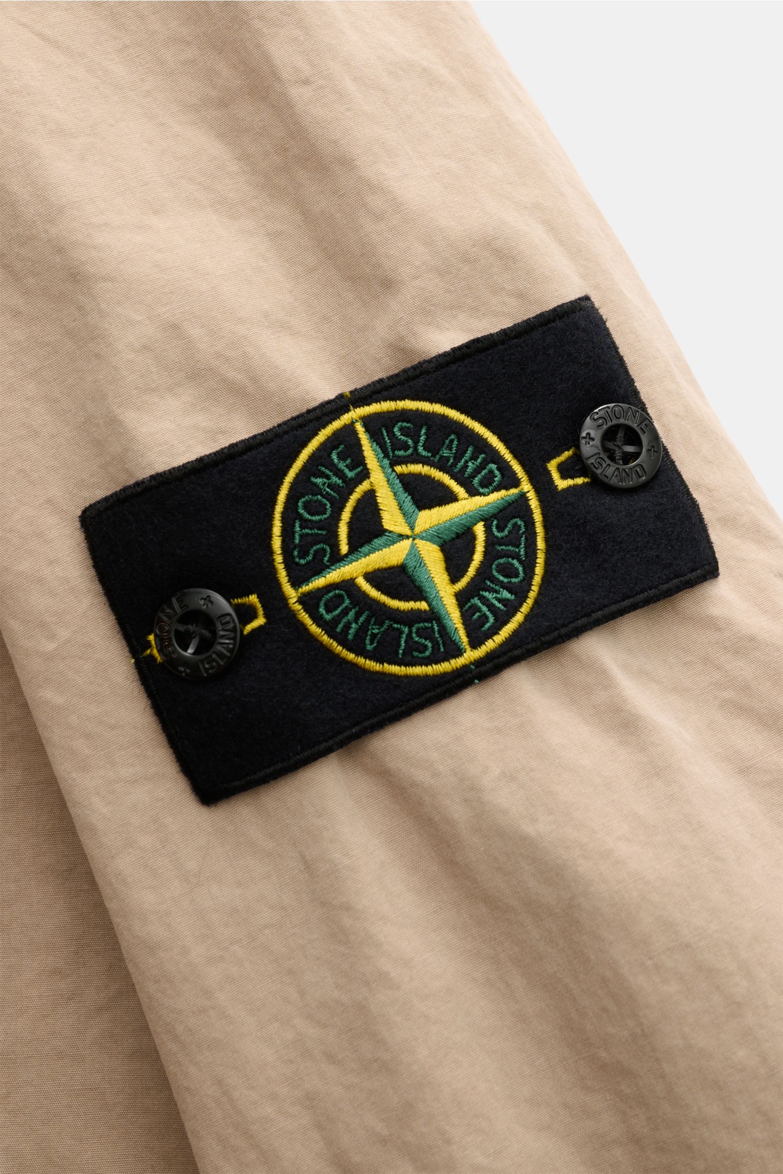 Stone Island Overshirt 'Brushed Canvas' beige, Nahaufnahme des Kompass-Badges am Oberarm, reine Baumwolle, Slim Fit, weicher Griff.