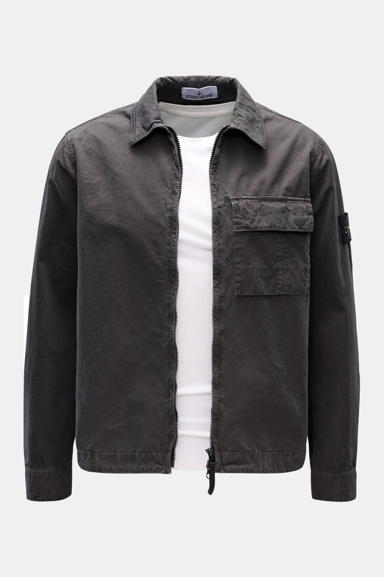 Front view of Stone Island Overshirt 'Brushed Canvas' dunkelgrau, a slim fit, dark gray cotton canvas overshirt with soft touch, two-way zipper, turn-down collar, chest pocket, buttoned cuffs, and compass badge on the upper arm, styled over a white shirt 