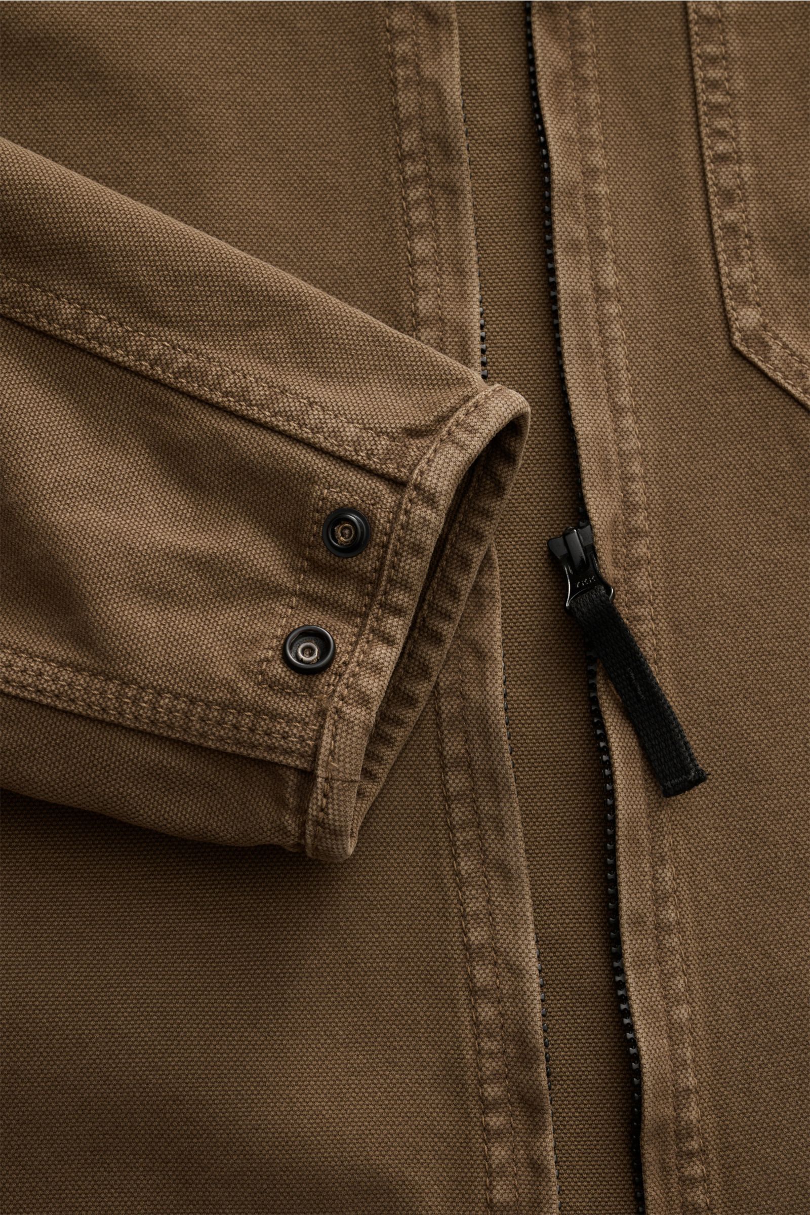 Close-up front view of Stone Island Overshirt 'Panama' khaki showing soft cotton fabric, slim fit, two-way zipper, buttoned cuff.

Vielseitiges Layering-Piece: Das zeitlose Overshirt von STONE ISLAND überzeugt mit seinem legeren Design und wird so zum 