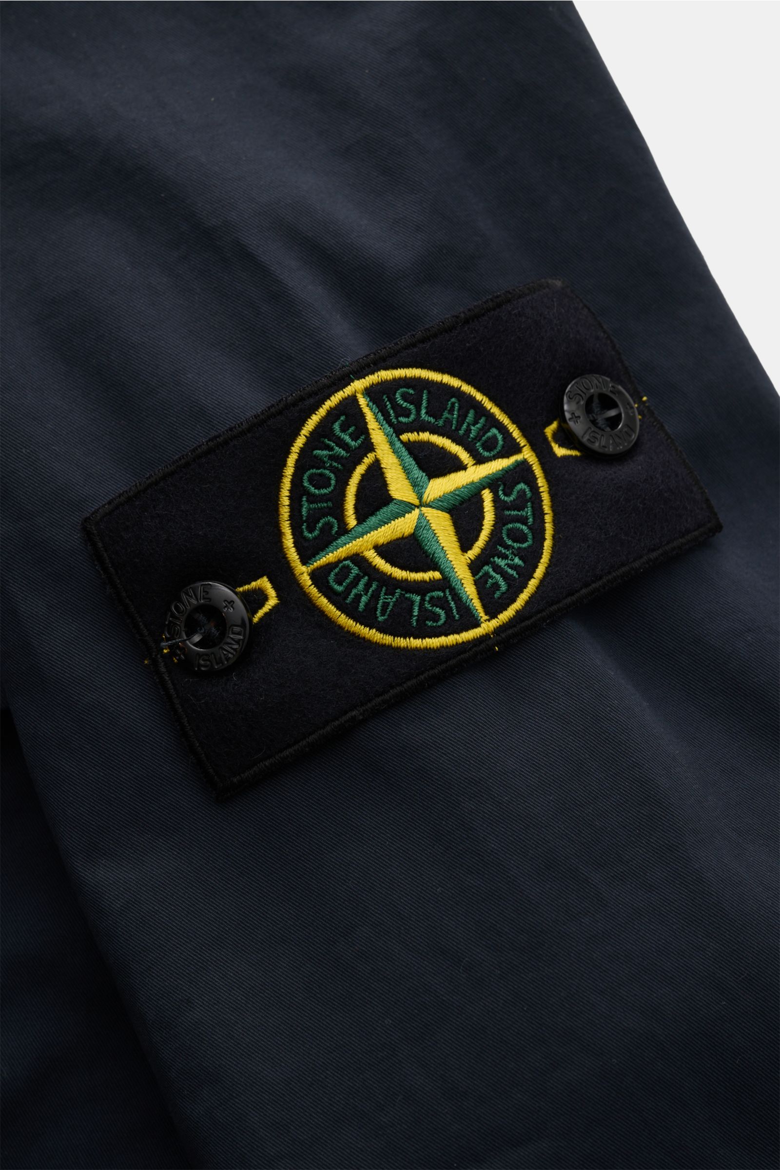 Close-up of the Stone Island Overshirt 'Stretch Cotton' navy showing the iconic compass badge on the sleeve, photographed from a detailed side angle.

Sportives Overshirt mit urbaner Lässigkeit: Dieser markante Hybrid aus Casual Hemd und Jacke von STON