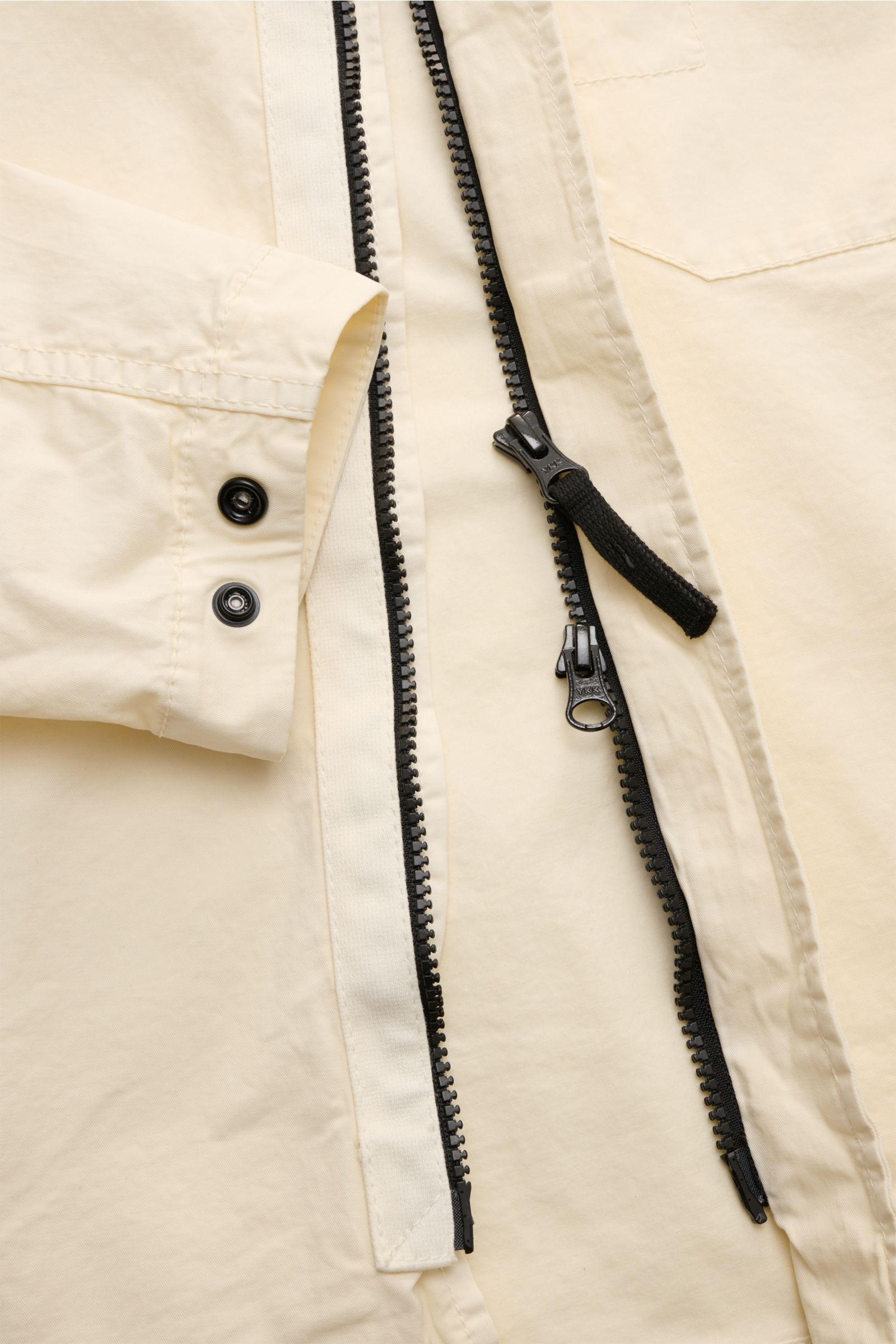 Stone Island Overshirt 'Stretch Cotton' creme close-up from above showing garment-dyed soft cotton, slim fit, two-way black zipper, snap cuffs, chest pocket, and signature compass badge. Sportives Overshirt mit urbaner Lässigkeit: Dieser markante Hybrid a