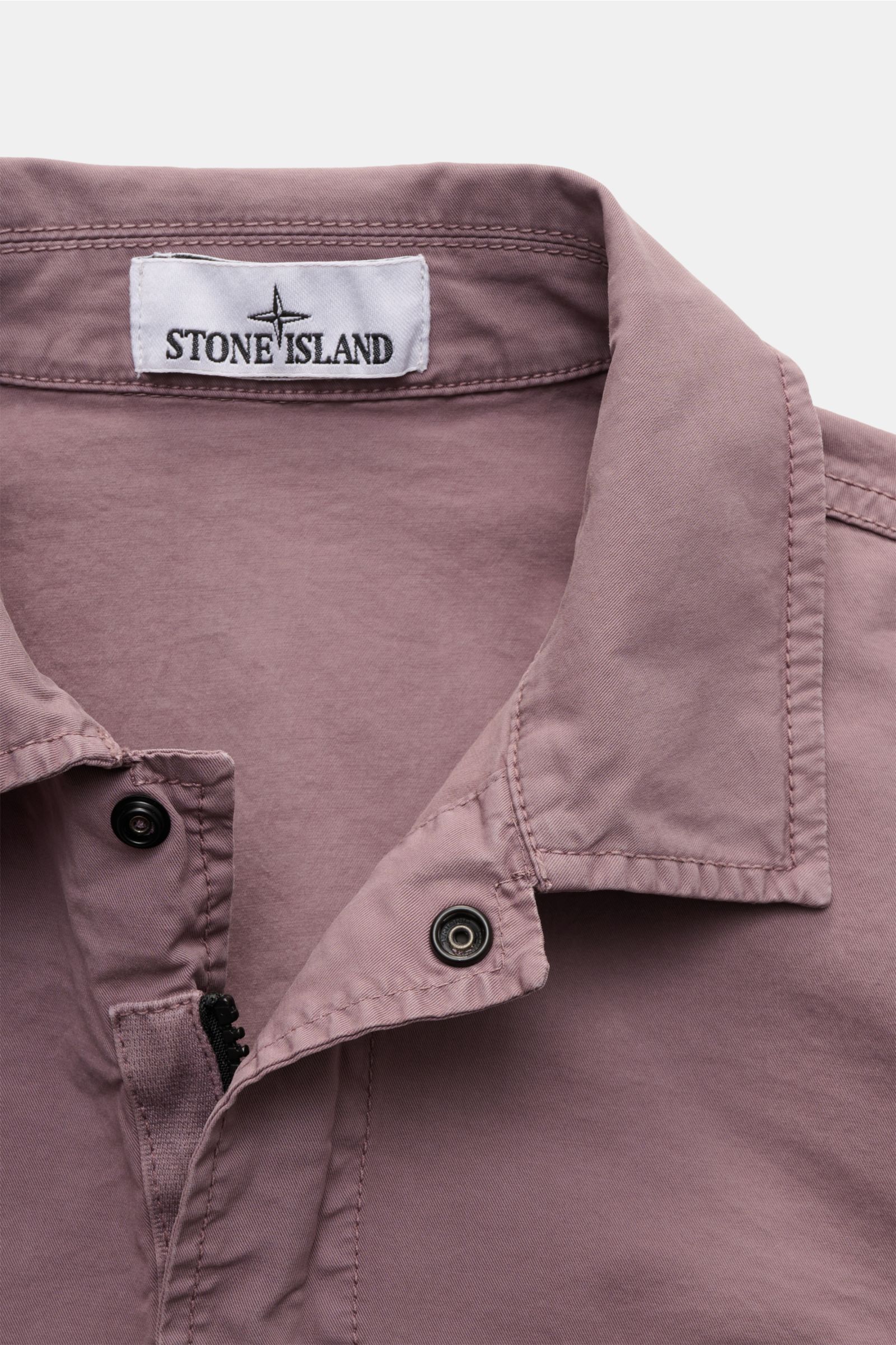 Close-up front view of Stone Island Overshirt 'Stretch Cotton' flieder in soft stretch cotton with garment-dyed vintage look, snap buttons, and collar.

Description: Sportives Overshirt mit urbaner Lässigkeit: Dieser markante Hybrid aus Casual Hemd und