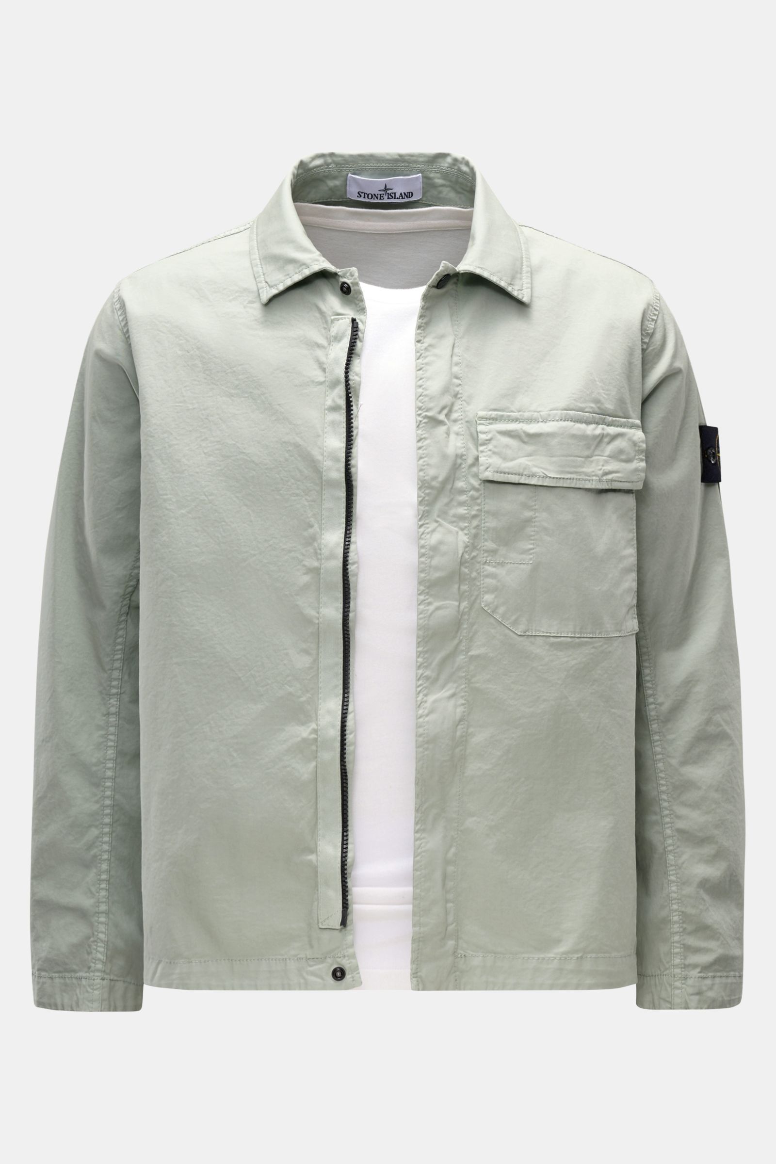 Front view of Stone Island Overshirt 'Stretch Cotton' salbei in light sage green, featuring soft, elastic cotton, slim fit, two-way zipper, snap buttons, turn-down collar, chest pocket with flap, signature compass badge on sleeve, and adjustable snap butt