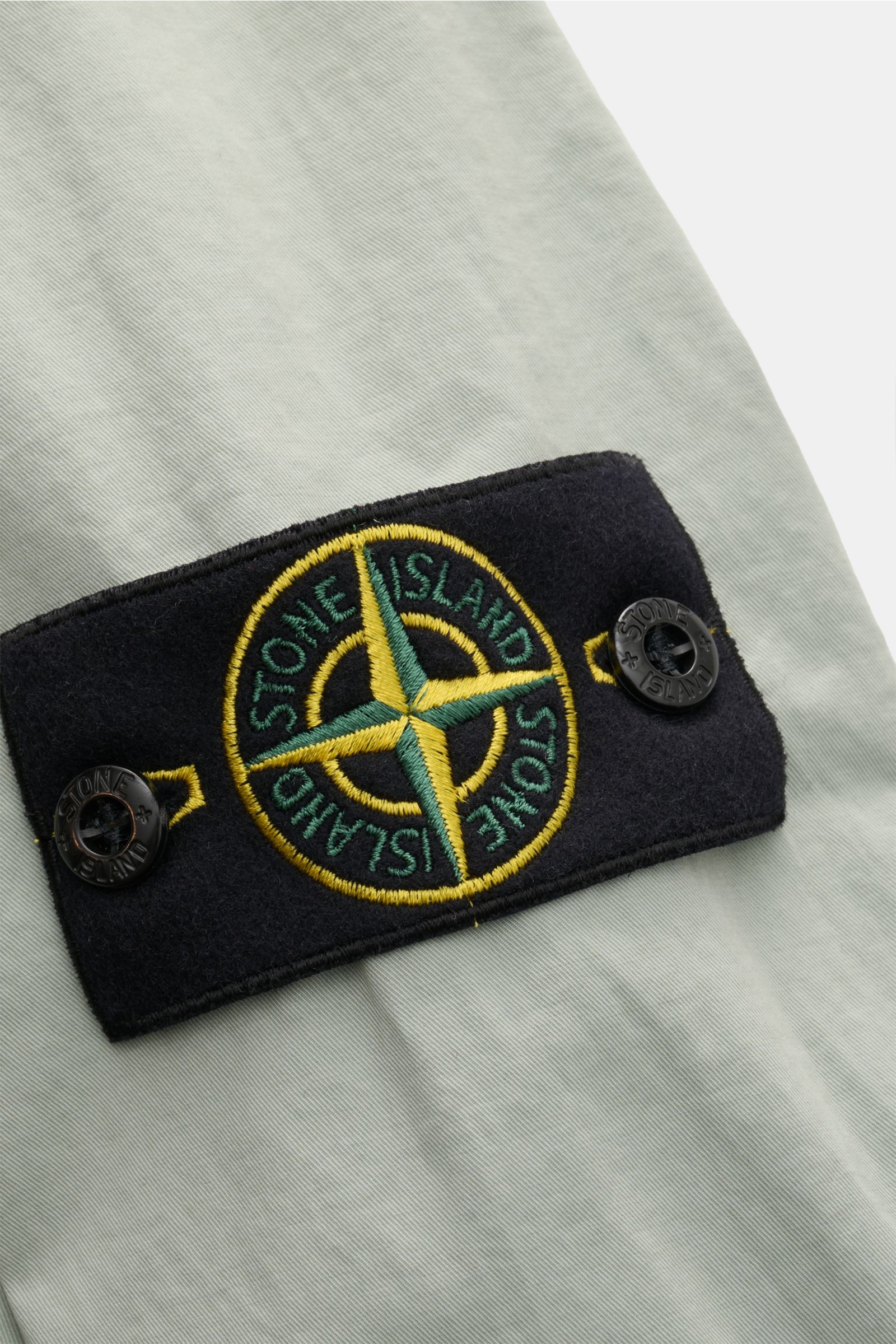 Close-up of the Stone Island Overshirt 'Stretch Cotton' salbei showing the iconic compass badge on the sleeve, photographed from a side angle. 

Sportives Overshirt mit urbaner Lässigkeit: Dieser markante Hybrid aus Casual Hemd und Jacke von STONE ISLA