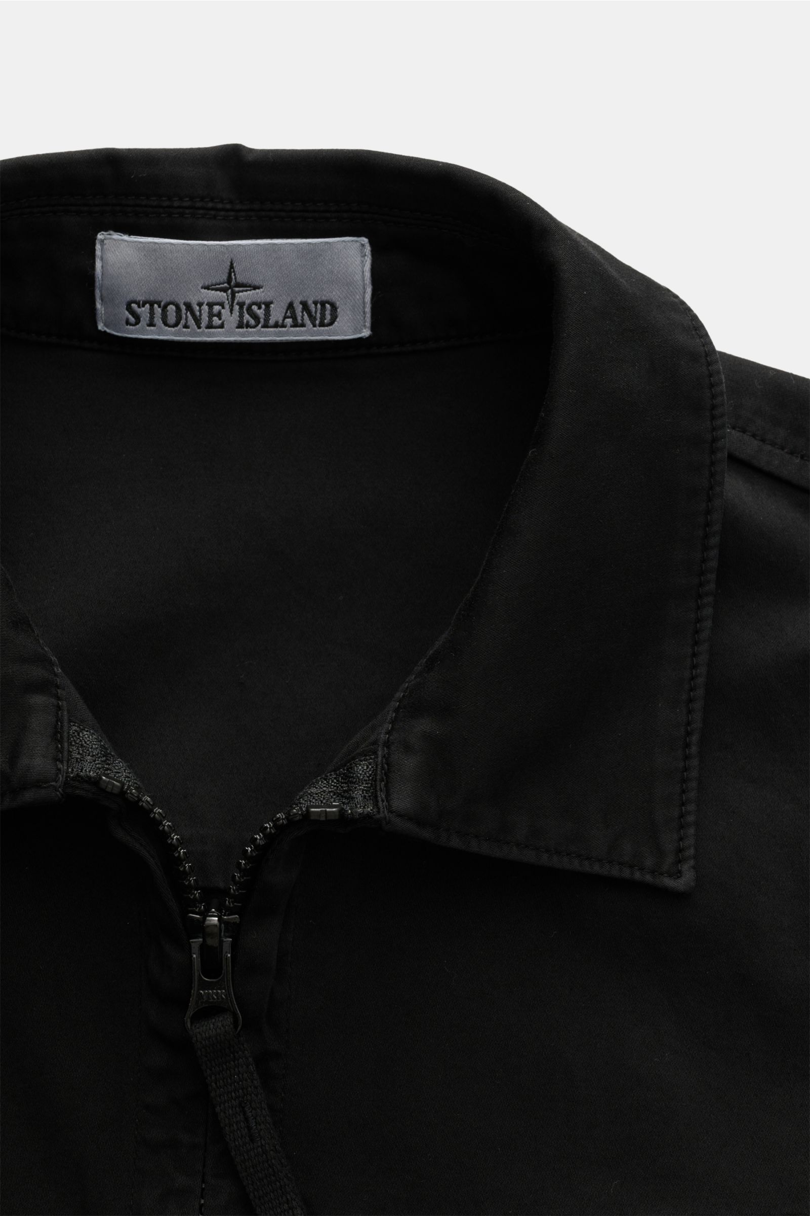 Stone Island Overshirt 'Cotton Satin' schwarz, Slim Fit aus elastischer Baumwolle mit Umlegekragen, Zwei-Wege-Reißverschluss, Brusttasche, Knopfärmeln, Kompass-Badge, Detailfoto von oben.