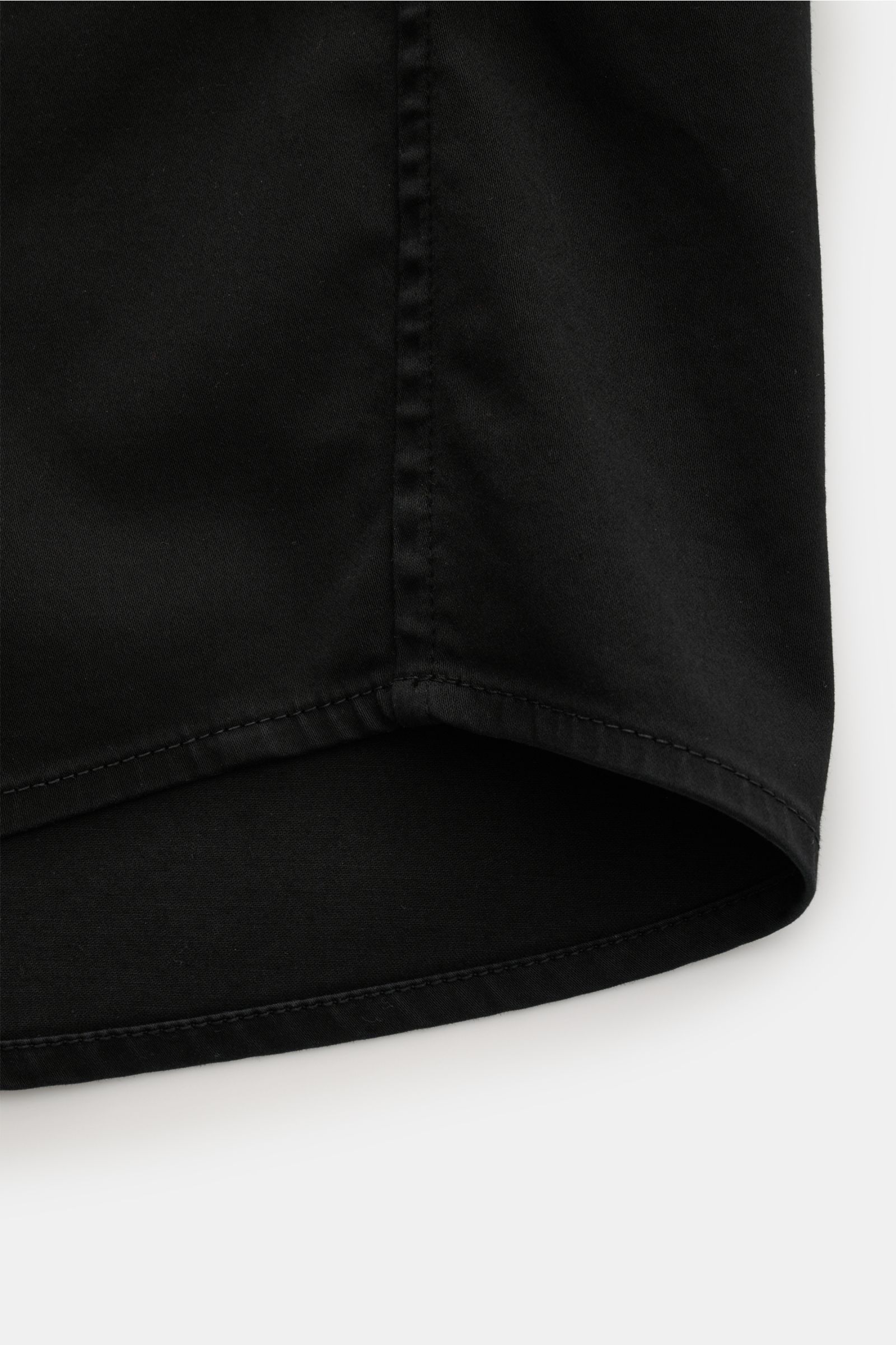 Nahaufnahme des unteren Saums des Stone Island Overshirt 'Cotton Satin' schwarz, Slim Fit, elastische Baumwolle, weicher Griff, von unten fotografiert.